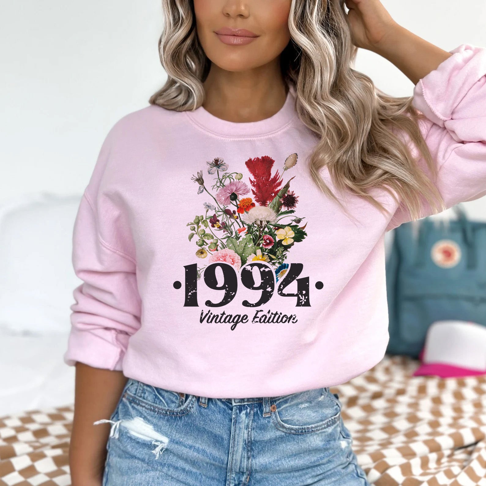 a woman wearing a pink sweatshirt with flowers on it