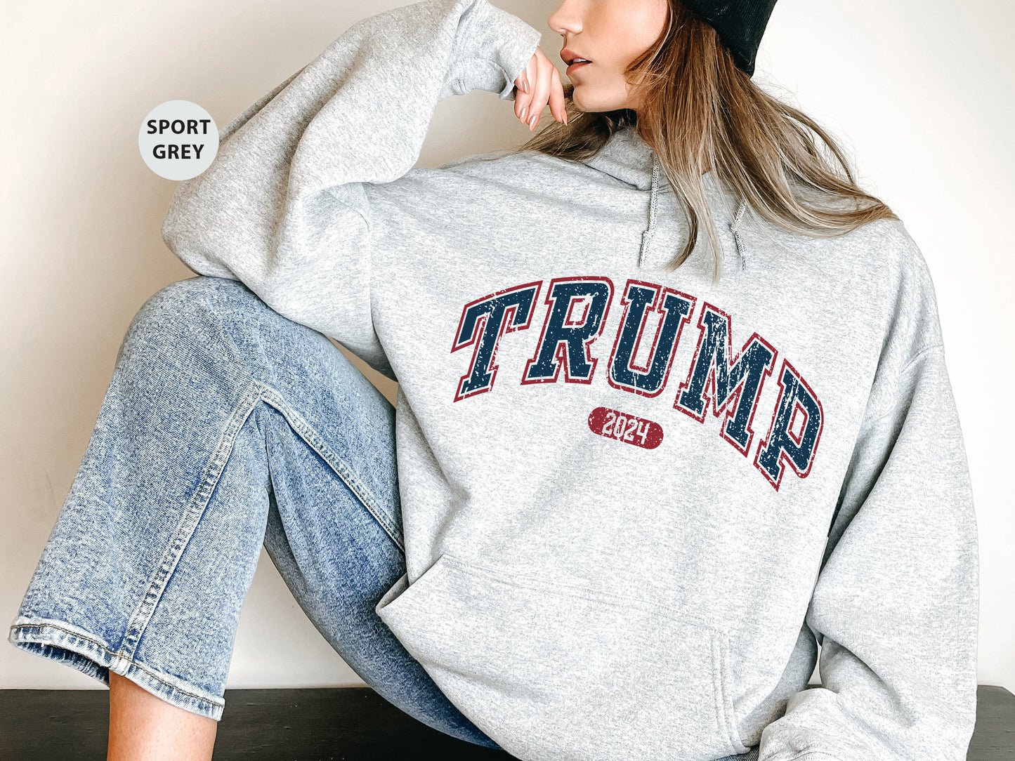 a woman sitting on the ground wearing a gray sweatshirt