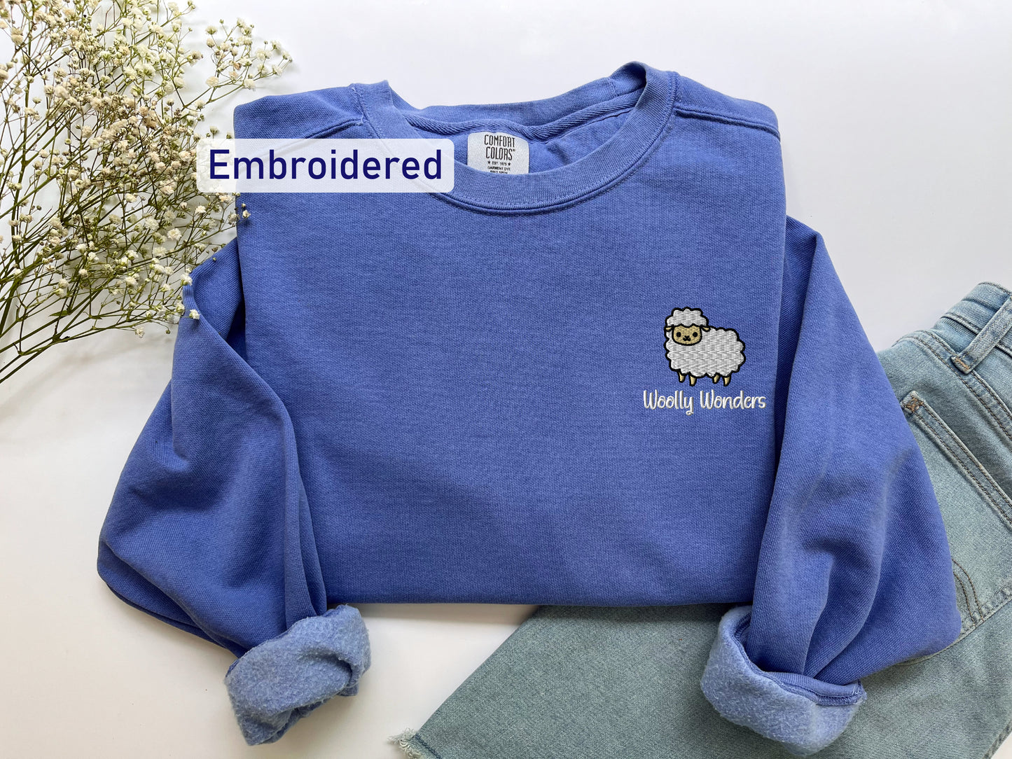 a blue sweater with a sheep embroidered on it