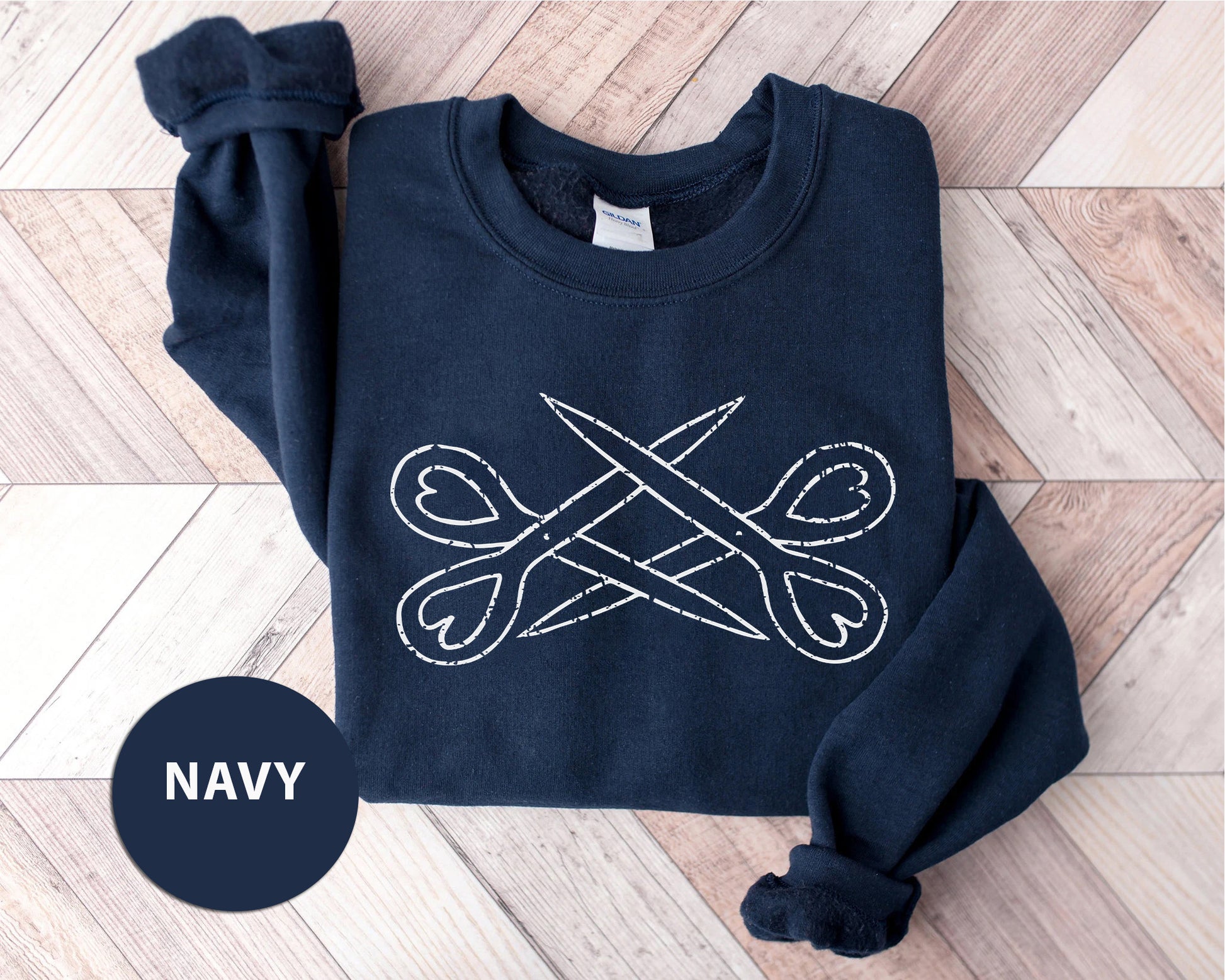 a navy sweatshirt with a pair of scissors on it