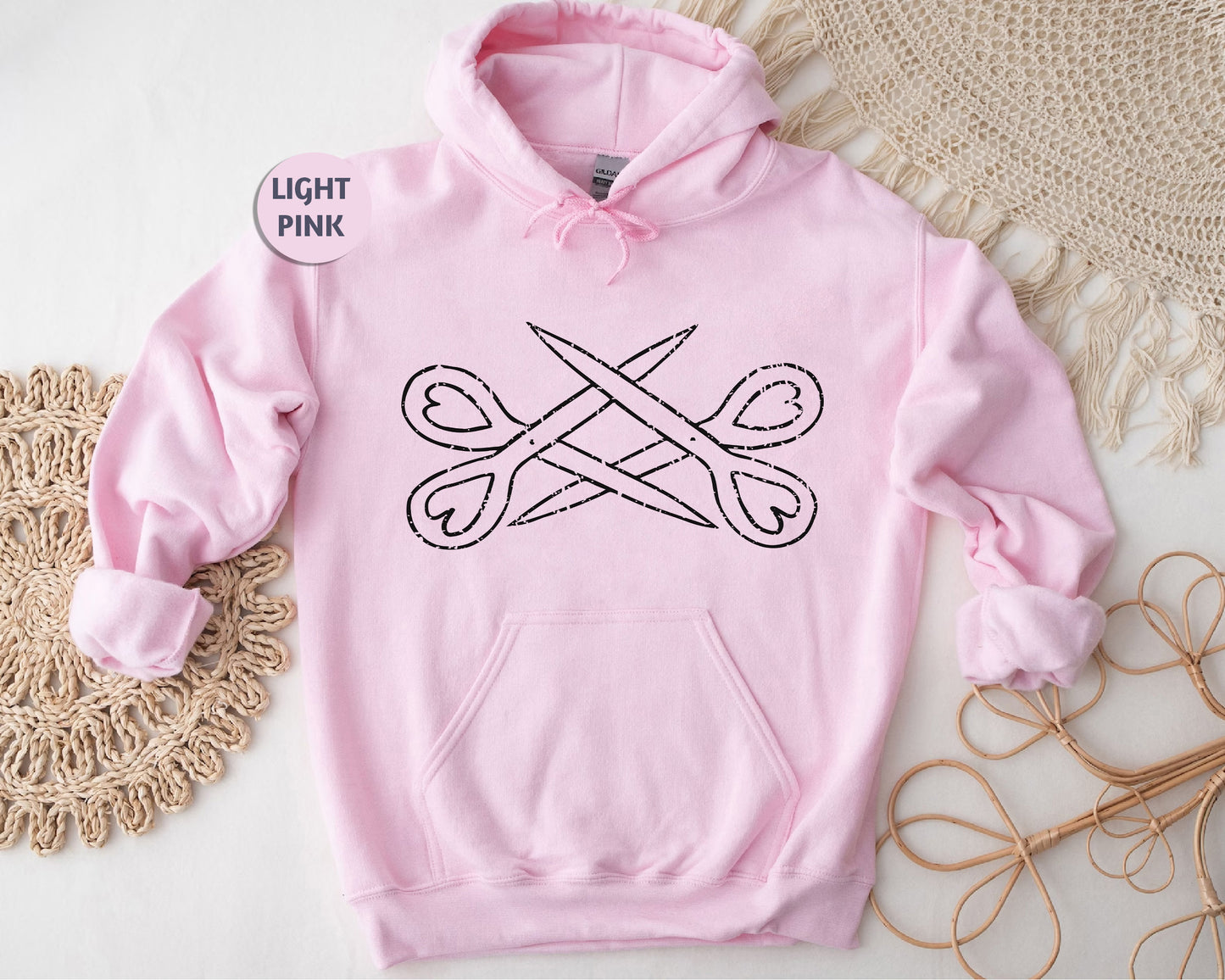 a pink hoodie with a pair of scissors on it