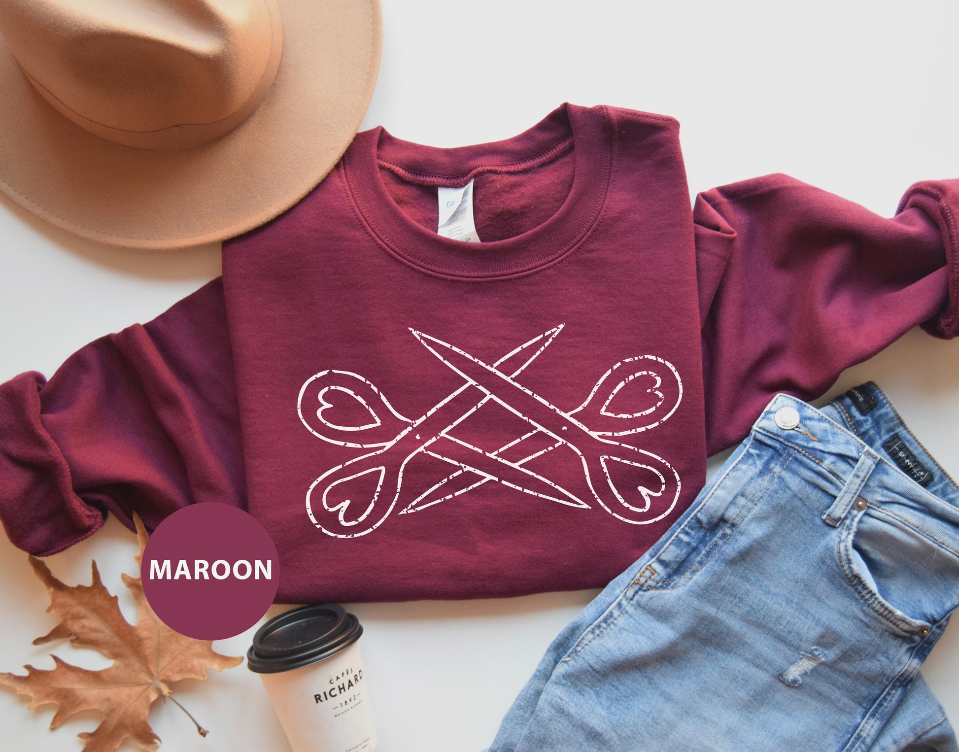 a pair of jeans, a hat, and a maroon shirt with scissors on it