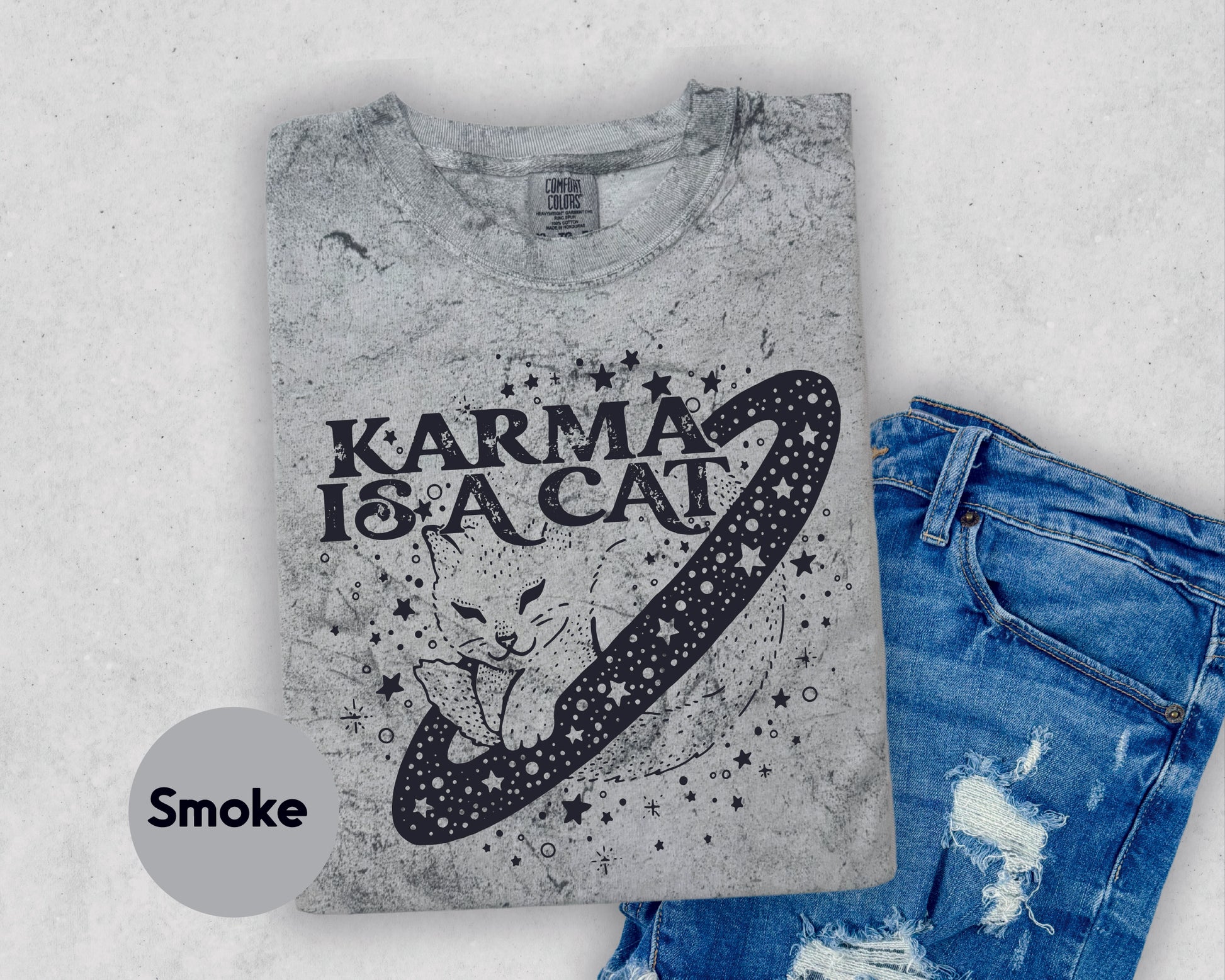 a t - shirt with a cat on it next to a pair of ripped jeans