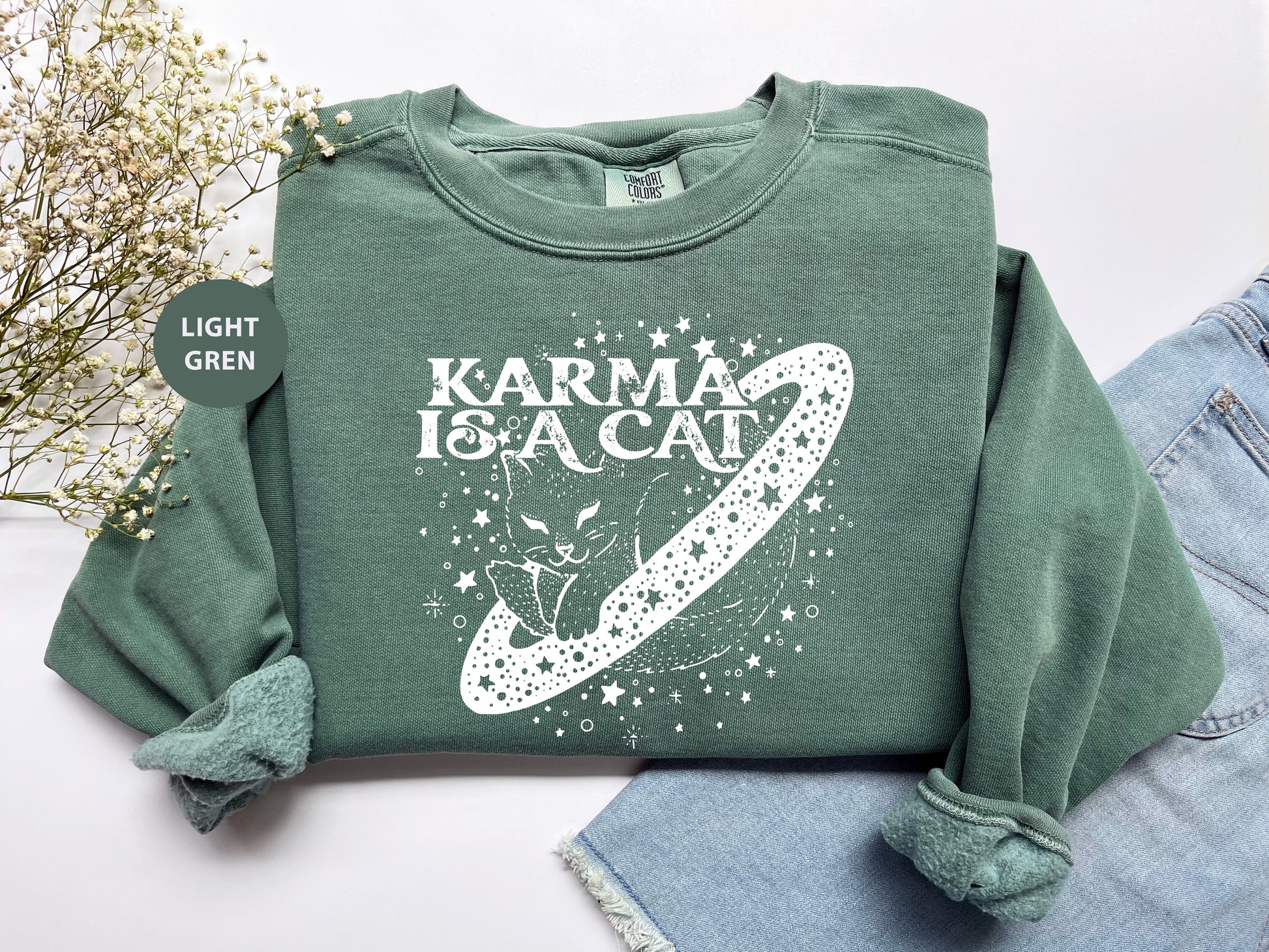 a green sweatshirt with the words karma is a cat on it