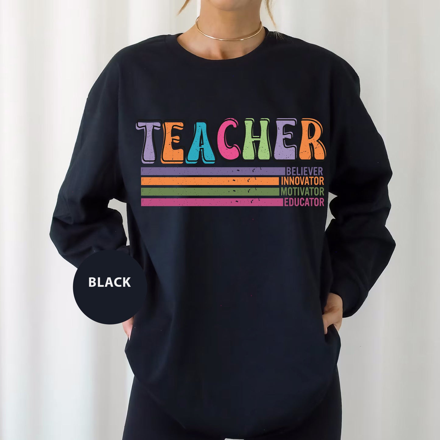 a woman wearing a black sweatshirt with a rainbow teacher on it