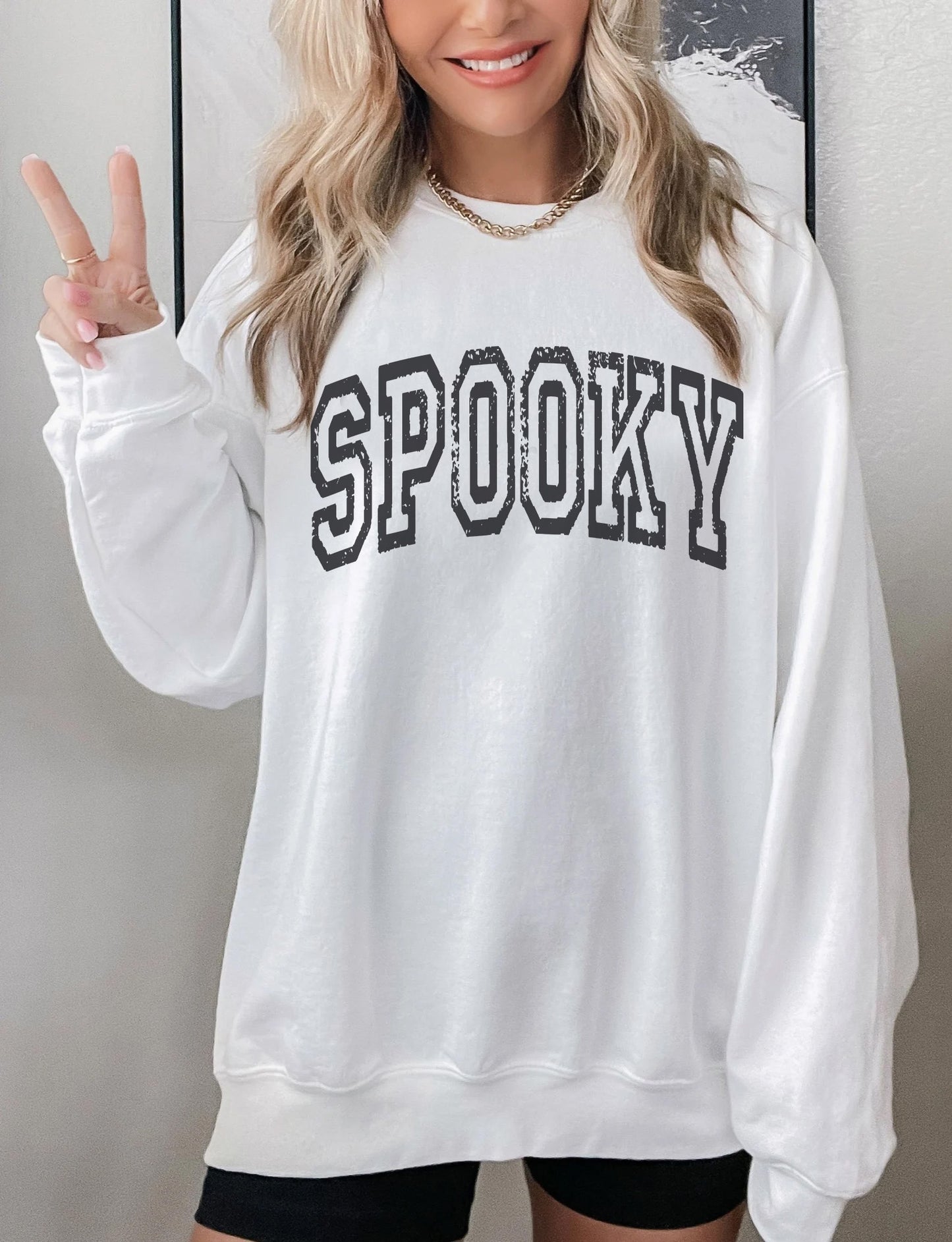 a woman wearing a white sweatshirt with the word spooky on it