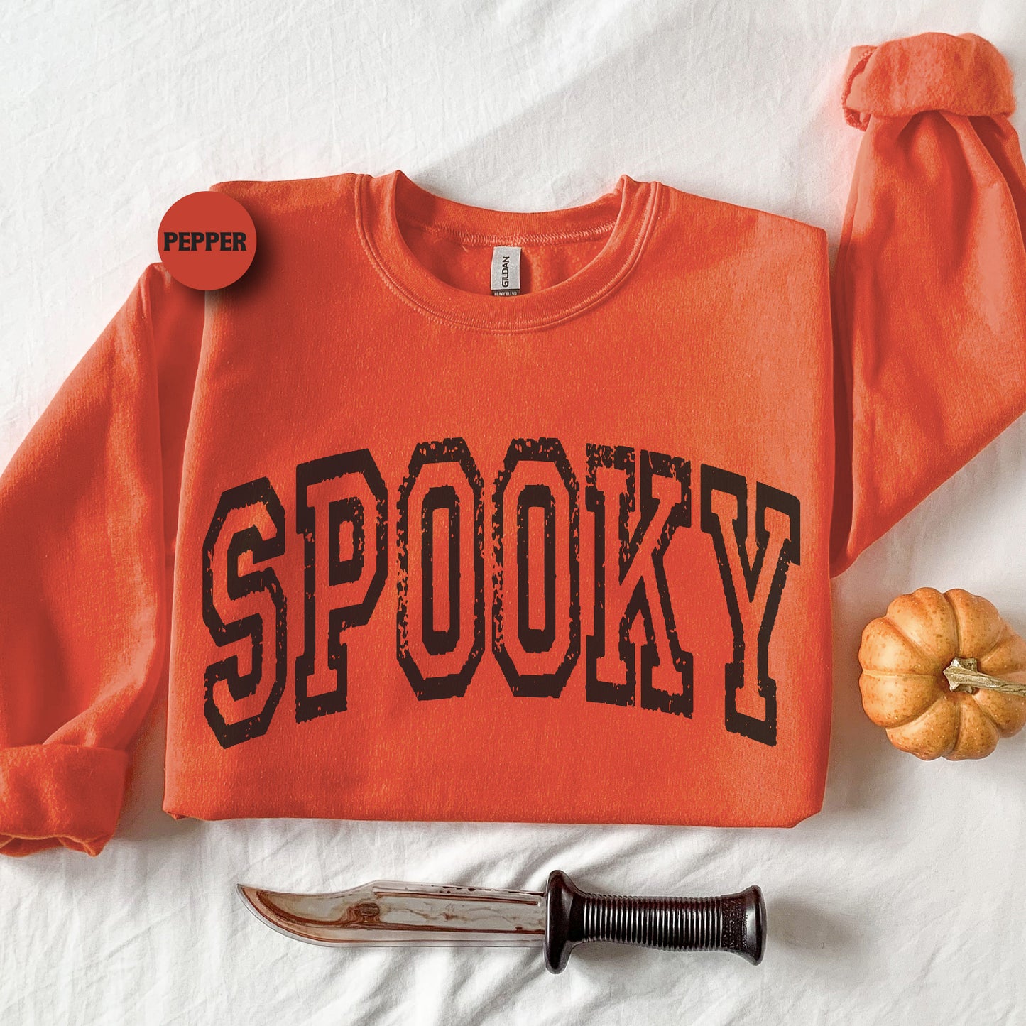 an orange shirt with the word spooky on it next to a knife and