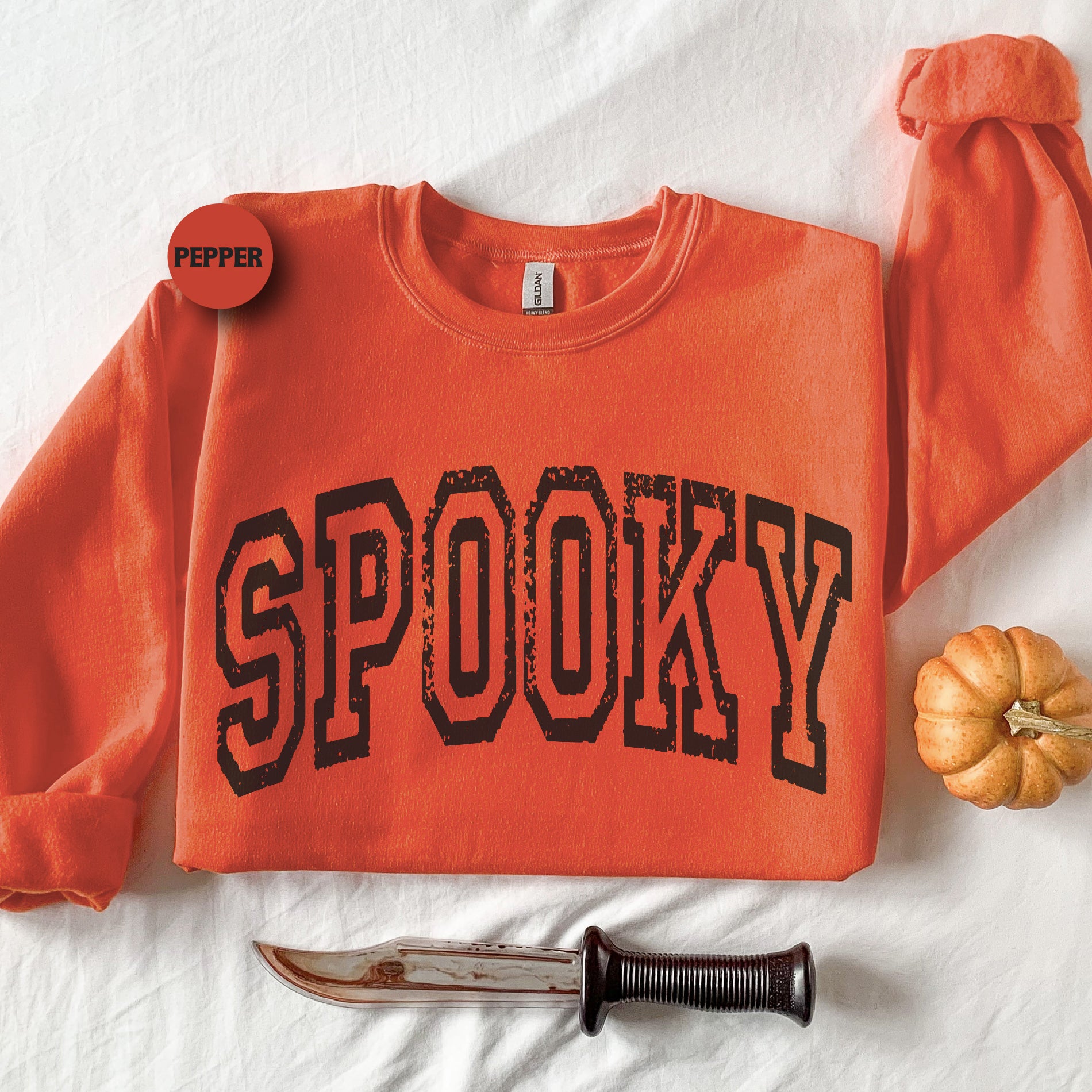 an orange shirt with the word spooky on it next to a knife and