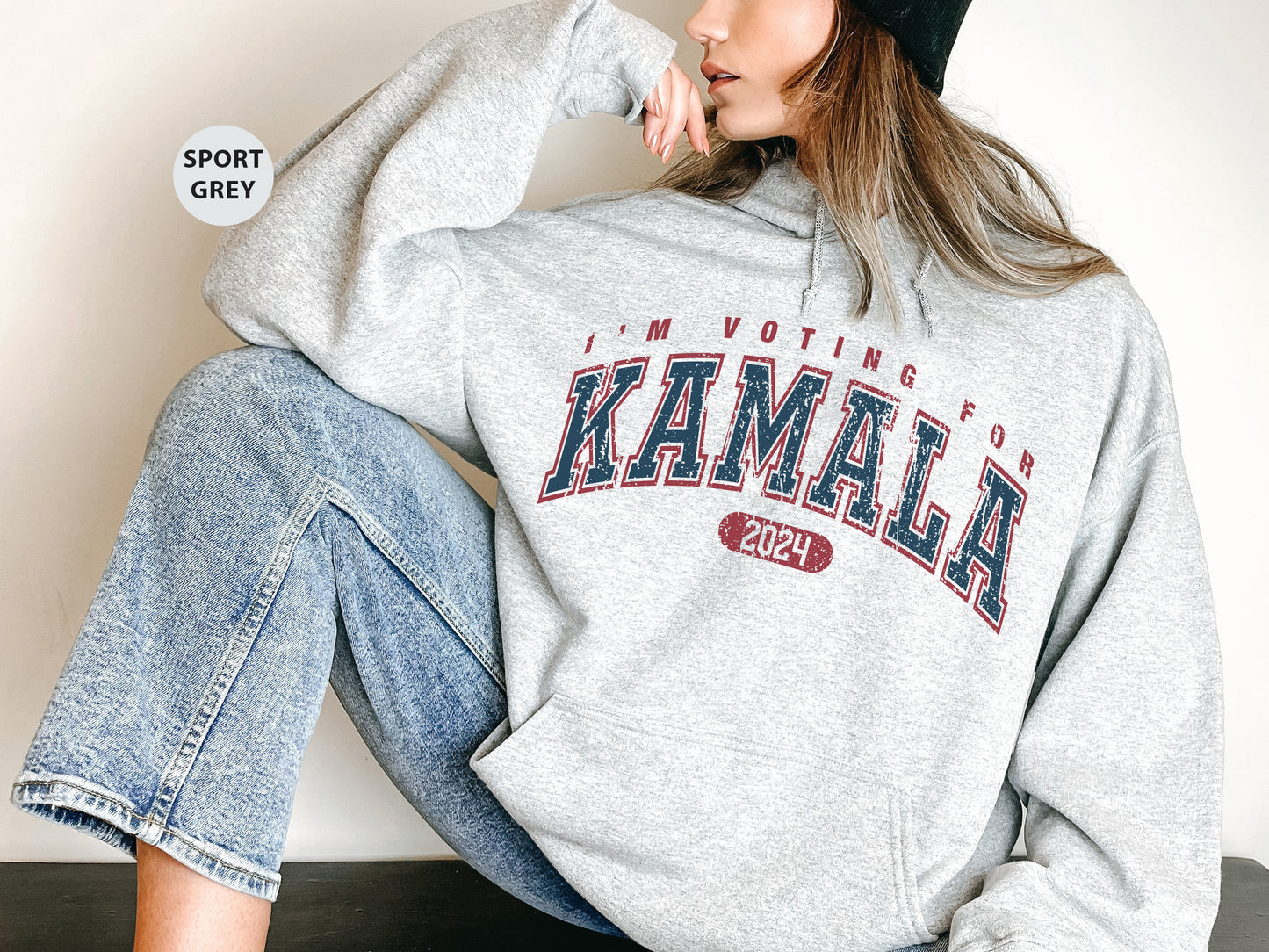 a woman sitting on the ground wearing a gray sweatshirt