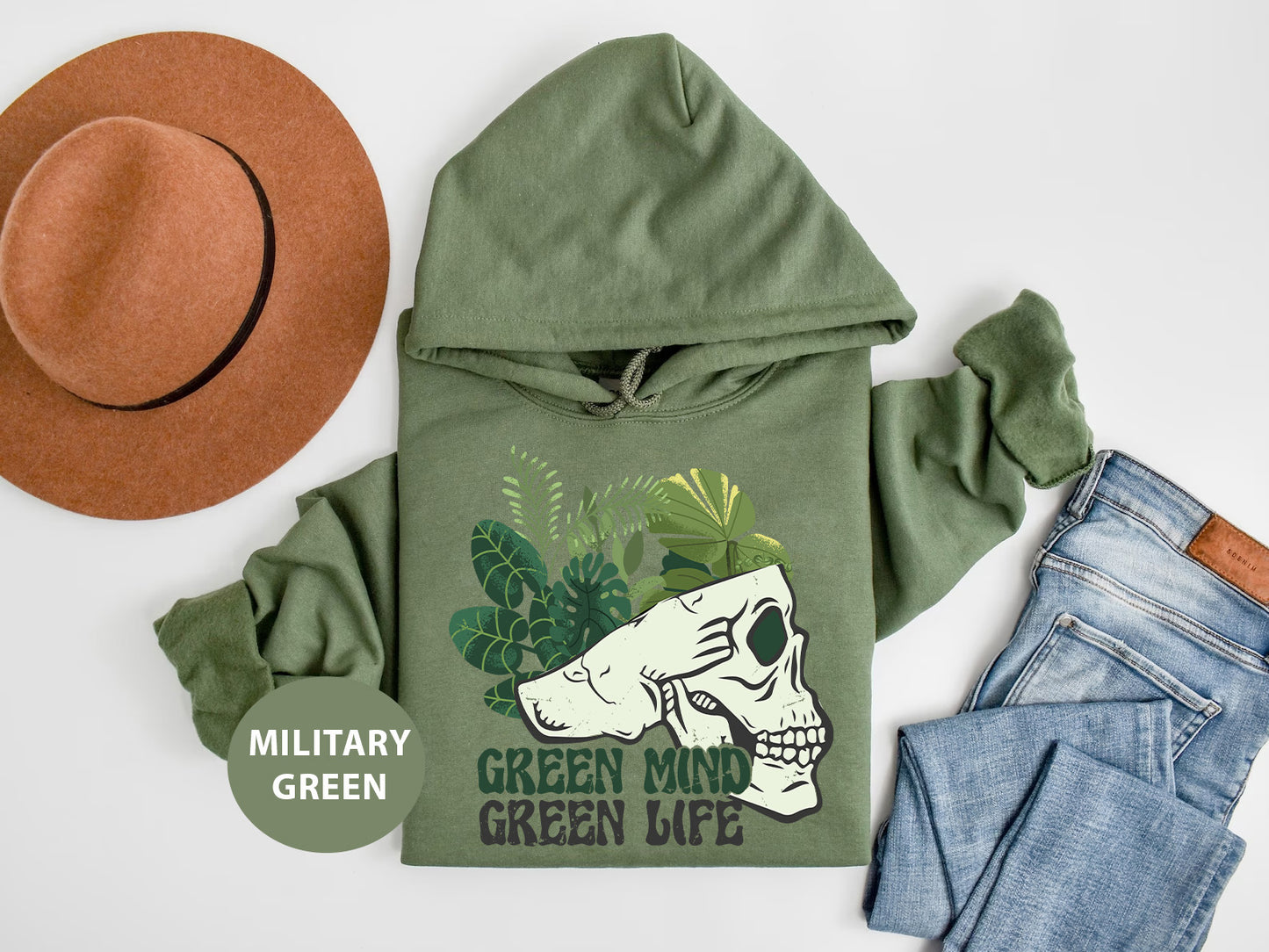a green hoodie with a skull on it next to jeans and a hat