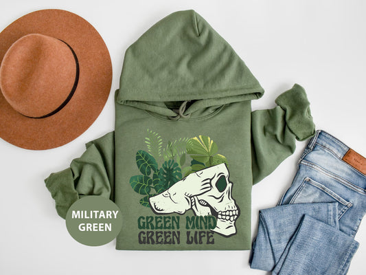 a green hoodie with a skull on it next to jeans and a hat