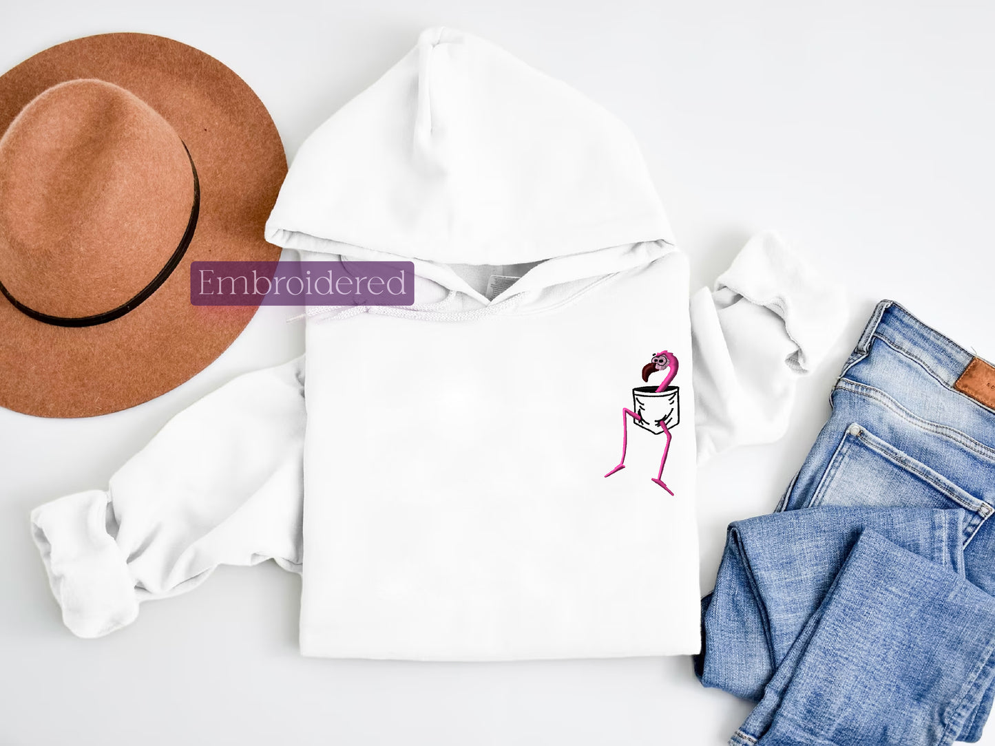 a white hoodie with a pink flamingo on it next to jeans and a