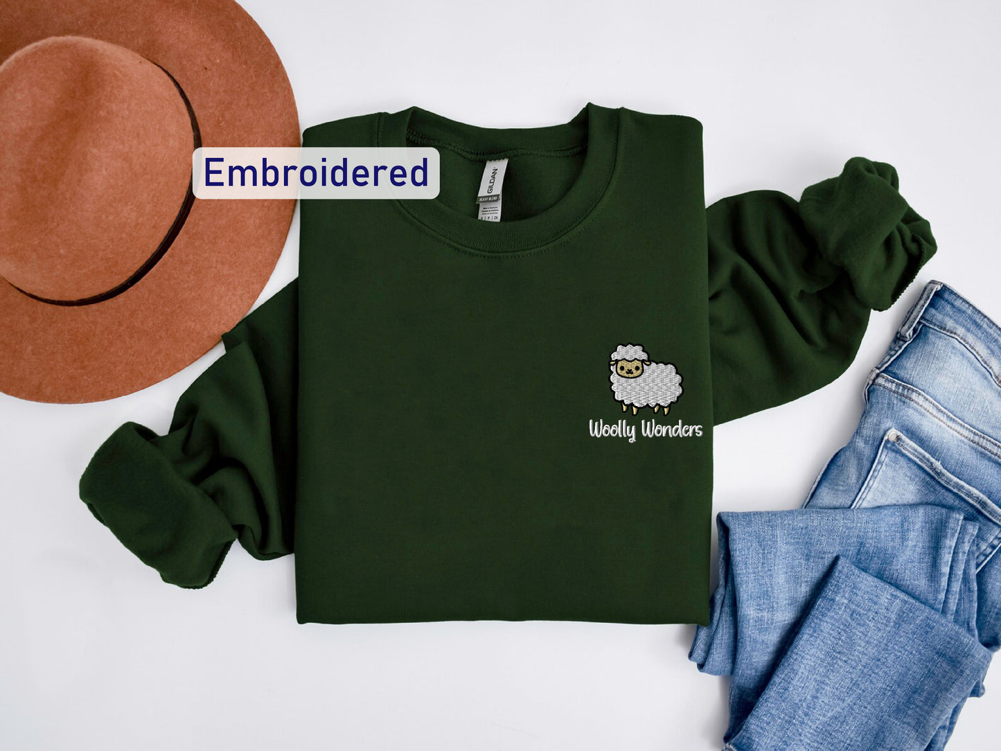 a green shirt with a sheep on it next to jeans and a hat