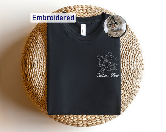 a black t - shirt with a cat on it sitting on a wicker basket