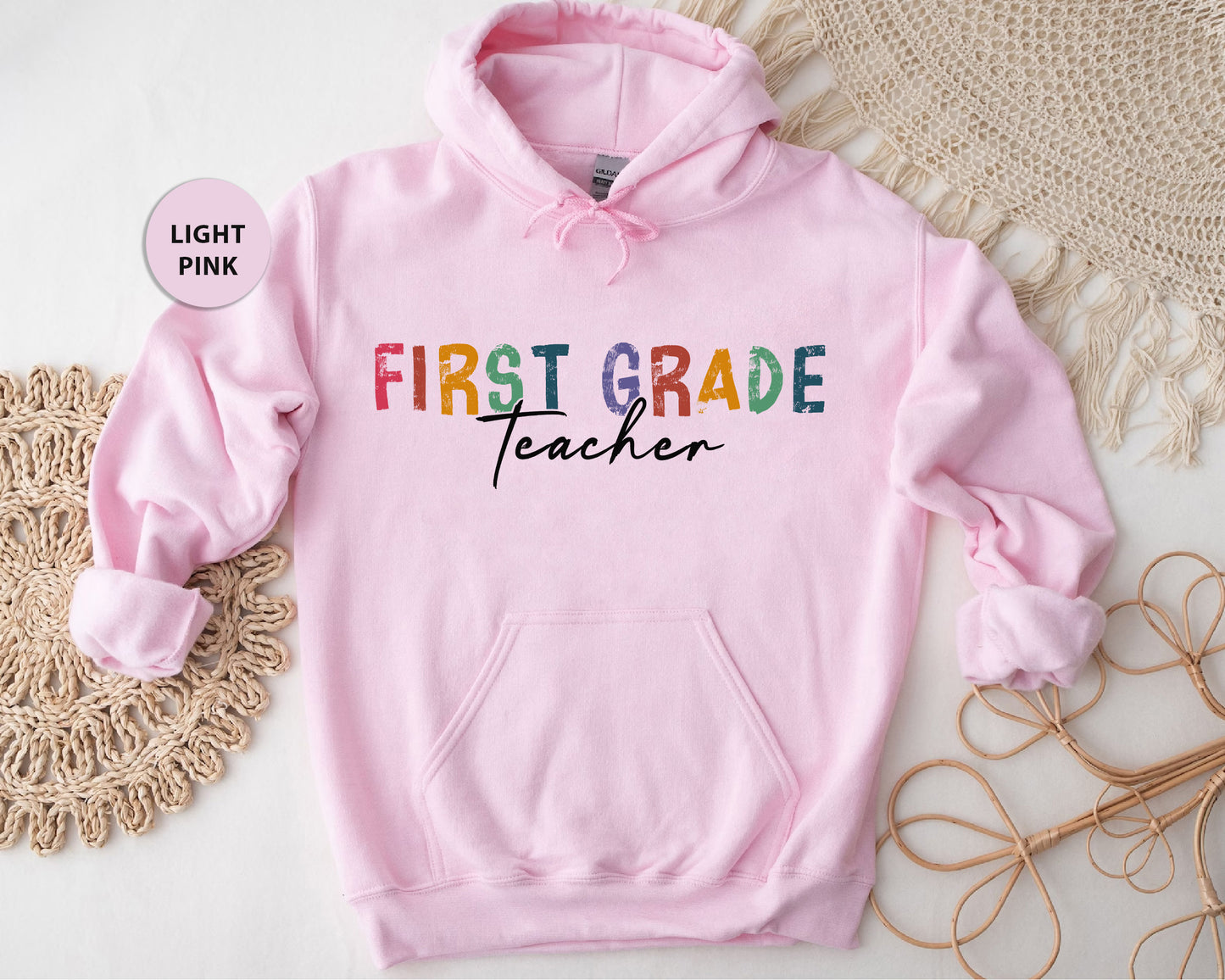 a pink hoodie with the words first grade teacher printed on it