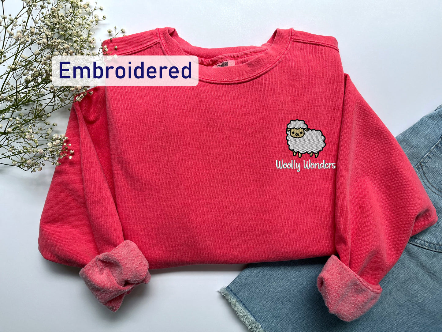 a pink sweater with a sheep embroidered on it