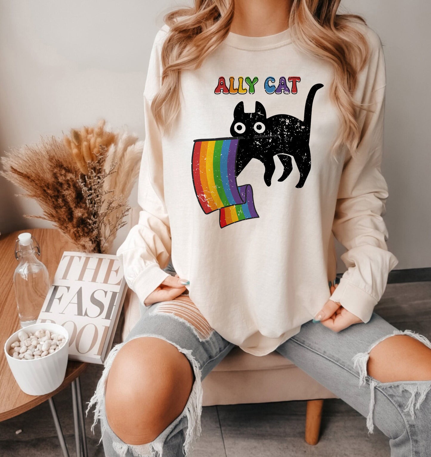 a woman sitting on a couch wearing a white shirt with a black cat on it