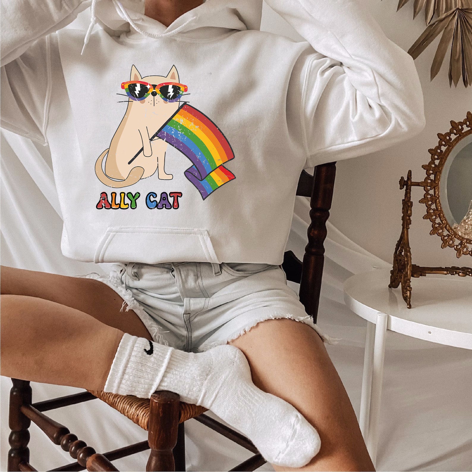 a woman sitting on a chair wearing a white hoodie with a cat on it