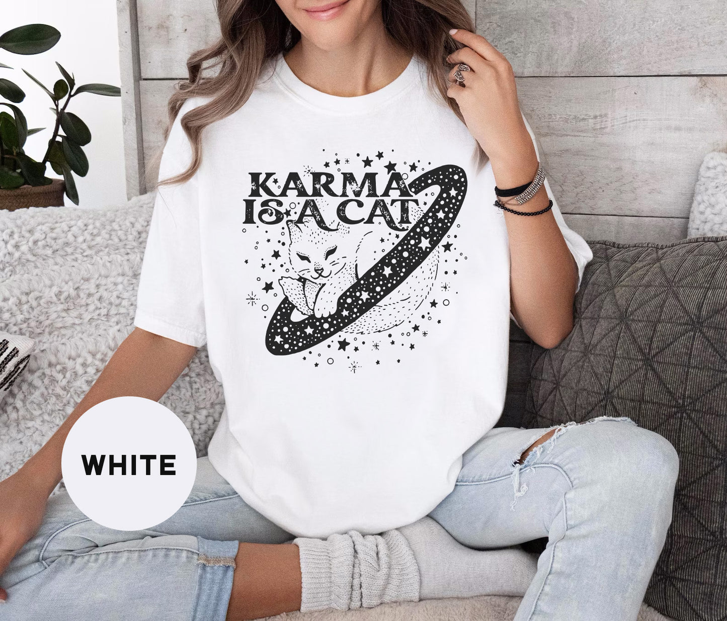 a woman sitting on a couch wearing a t - shirt that says karma is a