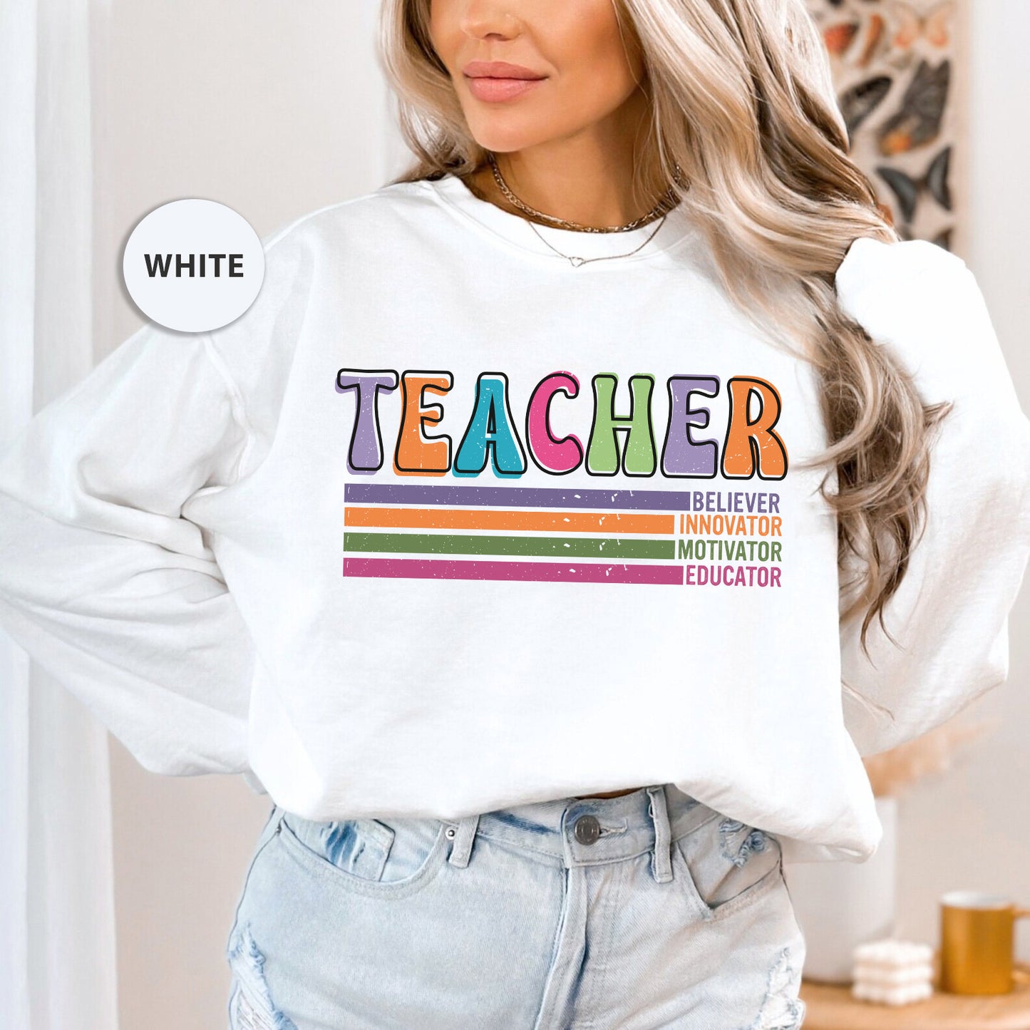 a woman wearing a white sweatshirt with the words teacher on it