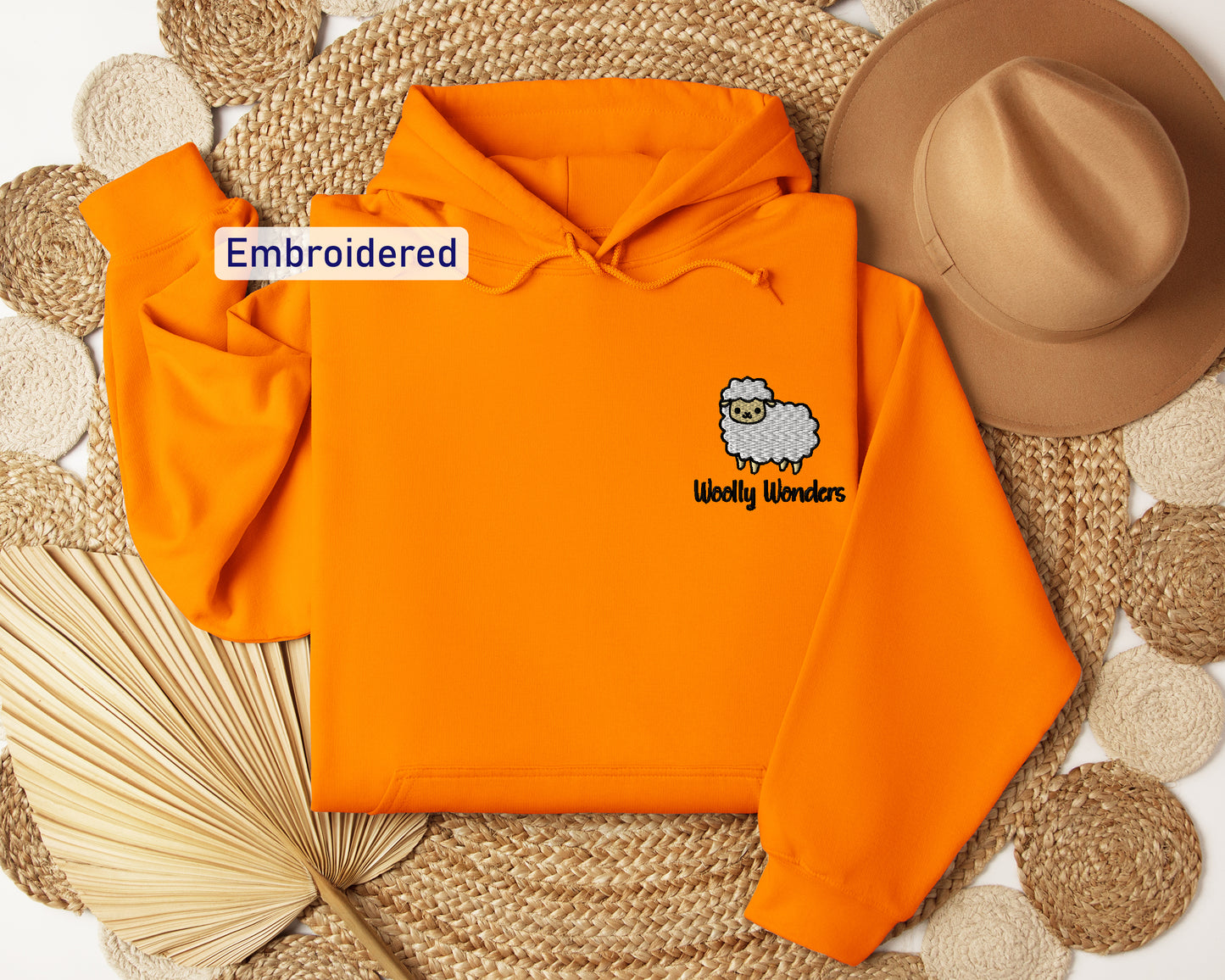an orange hoodie with an embroidered sheep on it