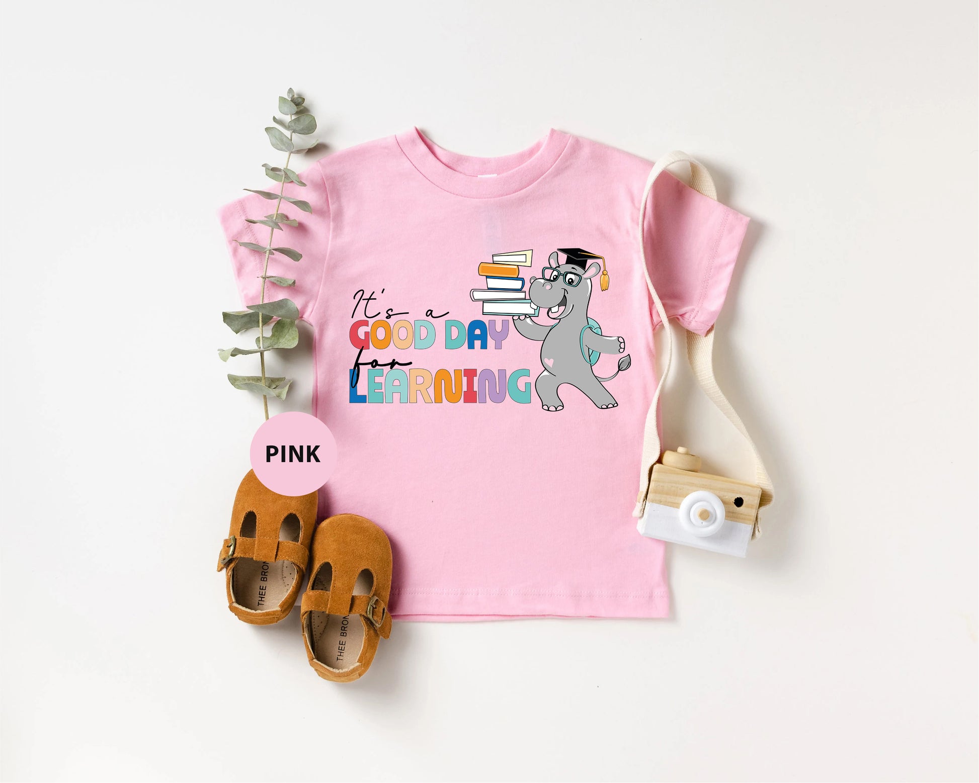 a pink shirt with a picture of a cat and a pair of shoes