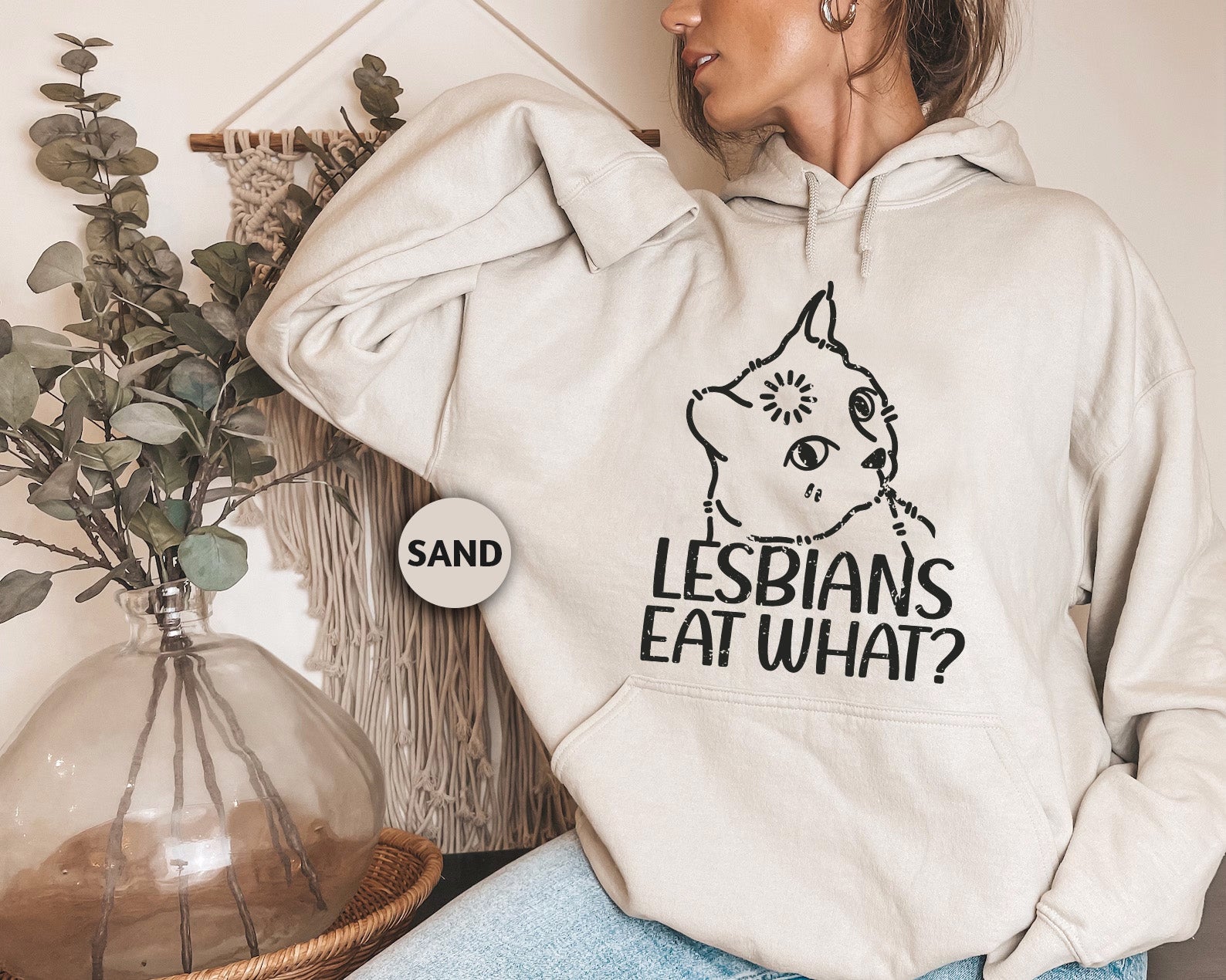 a woman wearing a sweatshirt with the words lesbians eat what? on it