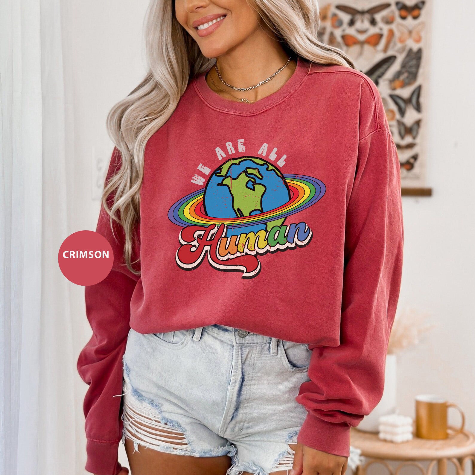 a woman wearing a red sweatshirt with the words, we are all human on it