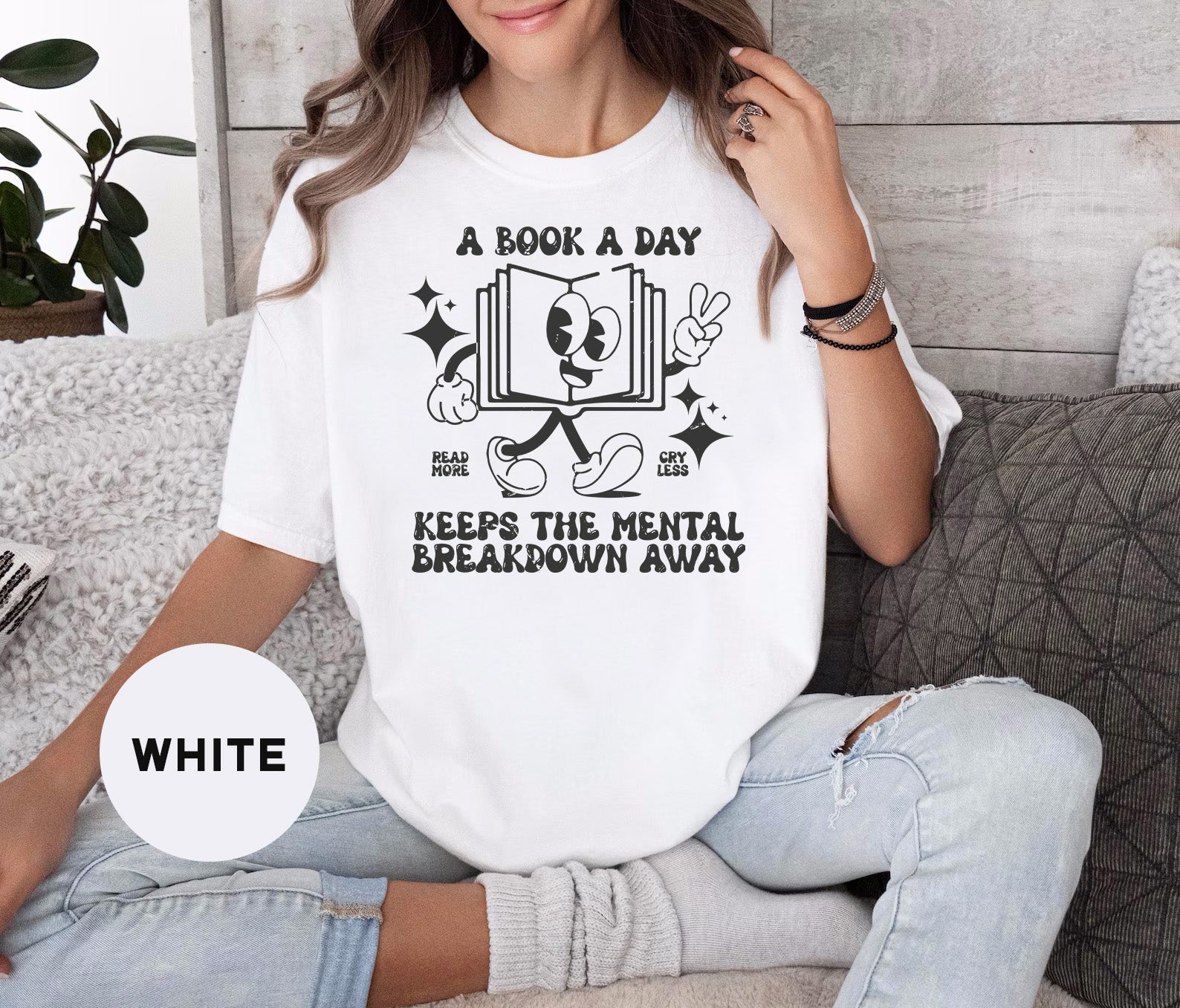 a woman sitting on a couch wearing a book a day shirt