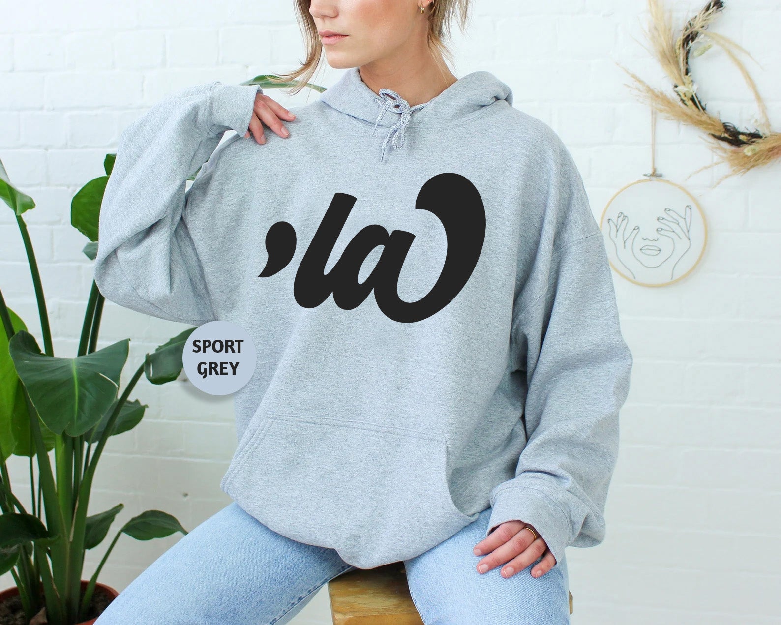 a woman sitting on a stool wearing a grey hoodie