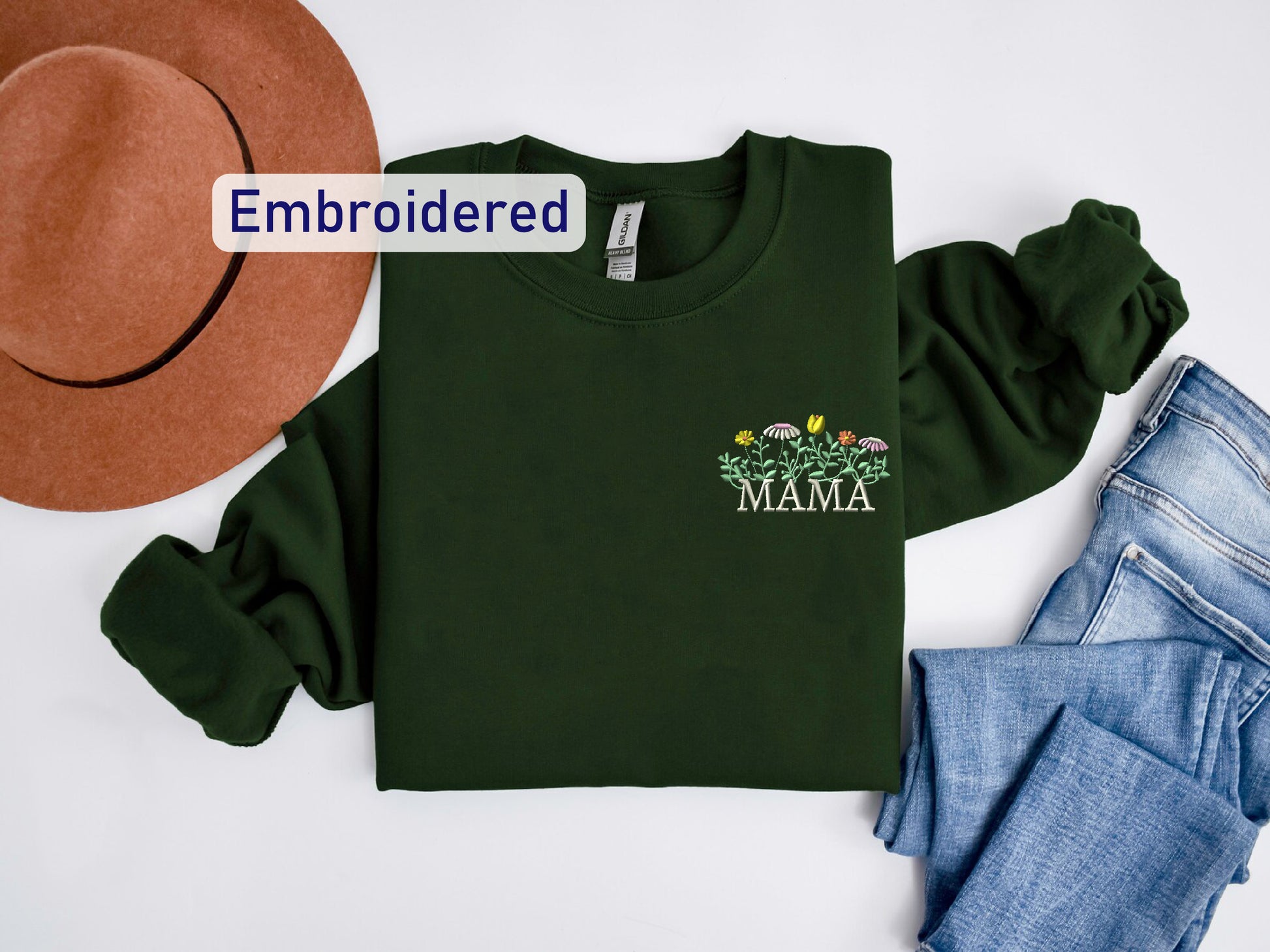 a green shirt with the name mama on it next to a hat and jeans