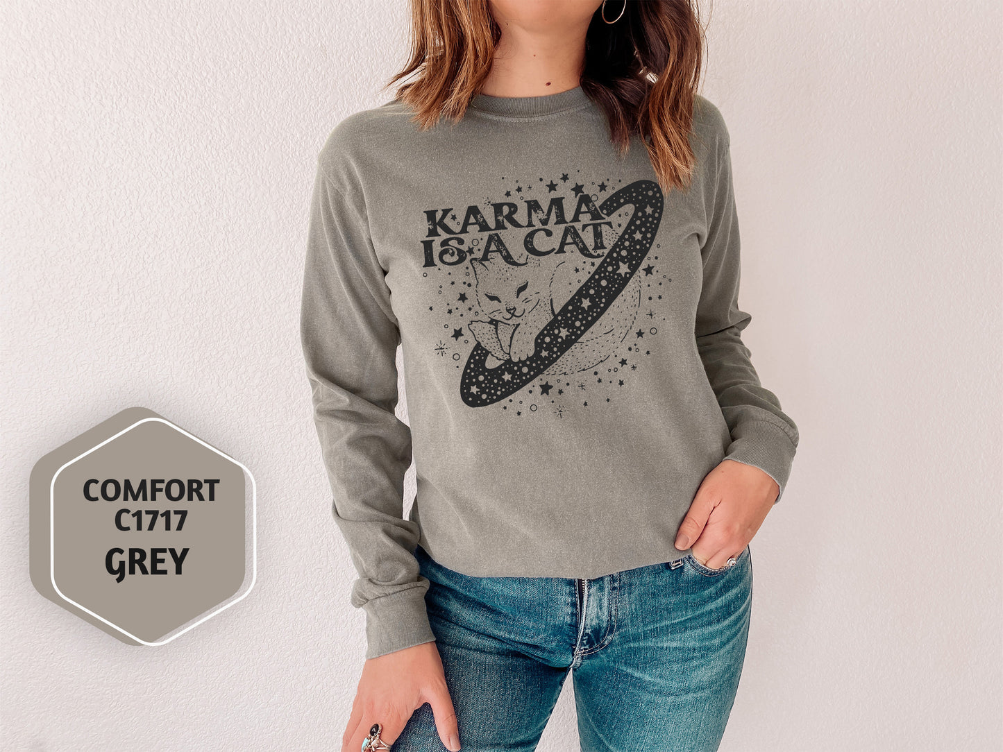 a woman standing next to a wall wearing a gray sweater