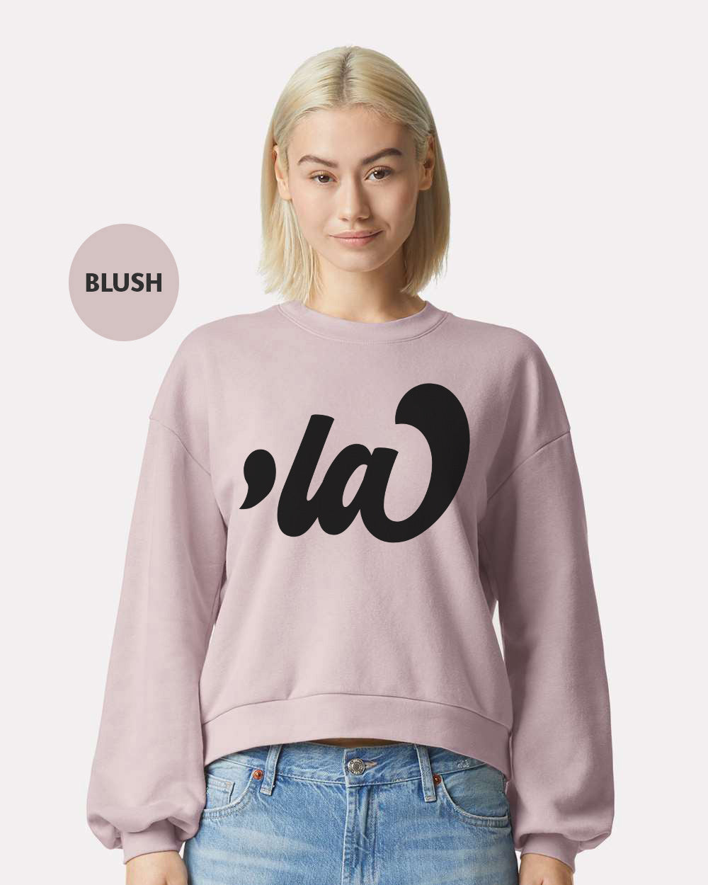 a woman with blonde hair wearing a pink sweatshirt and jeans