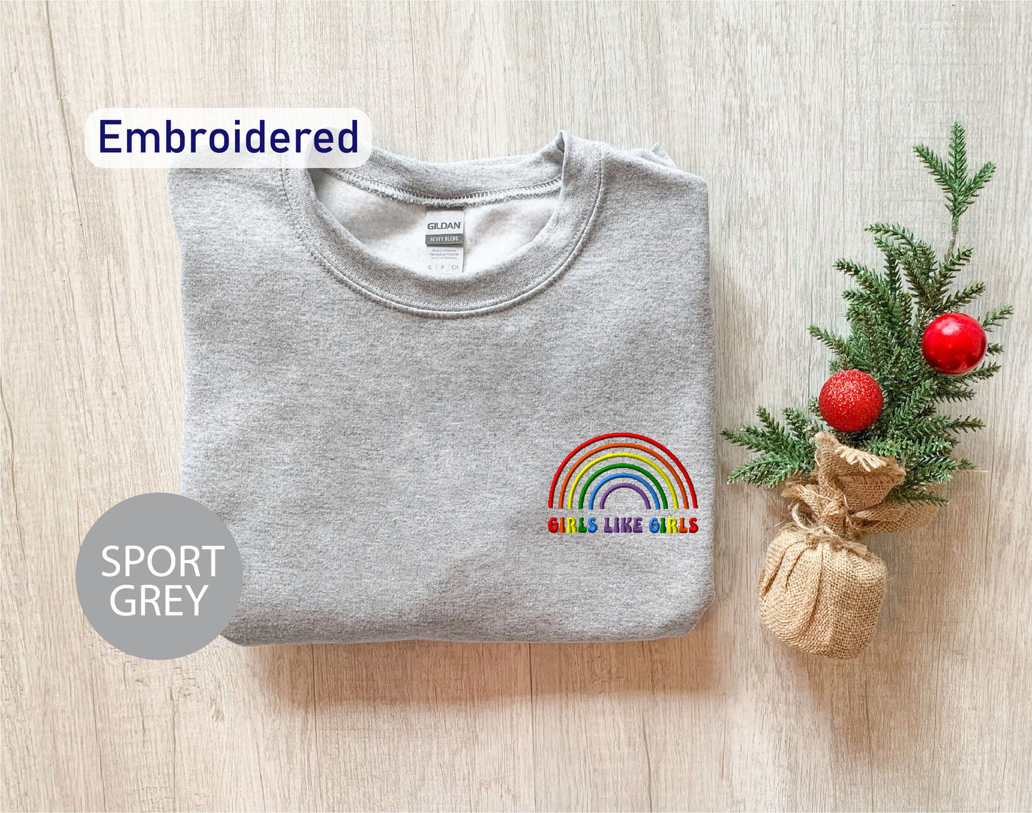 a t - shirt with a rainbow embroidered on it next to a christmas tree