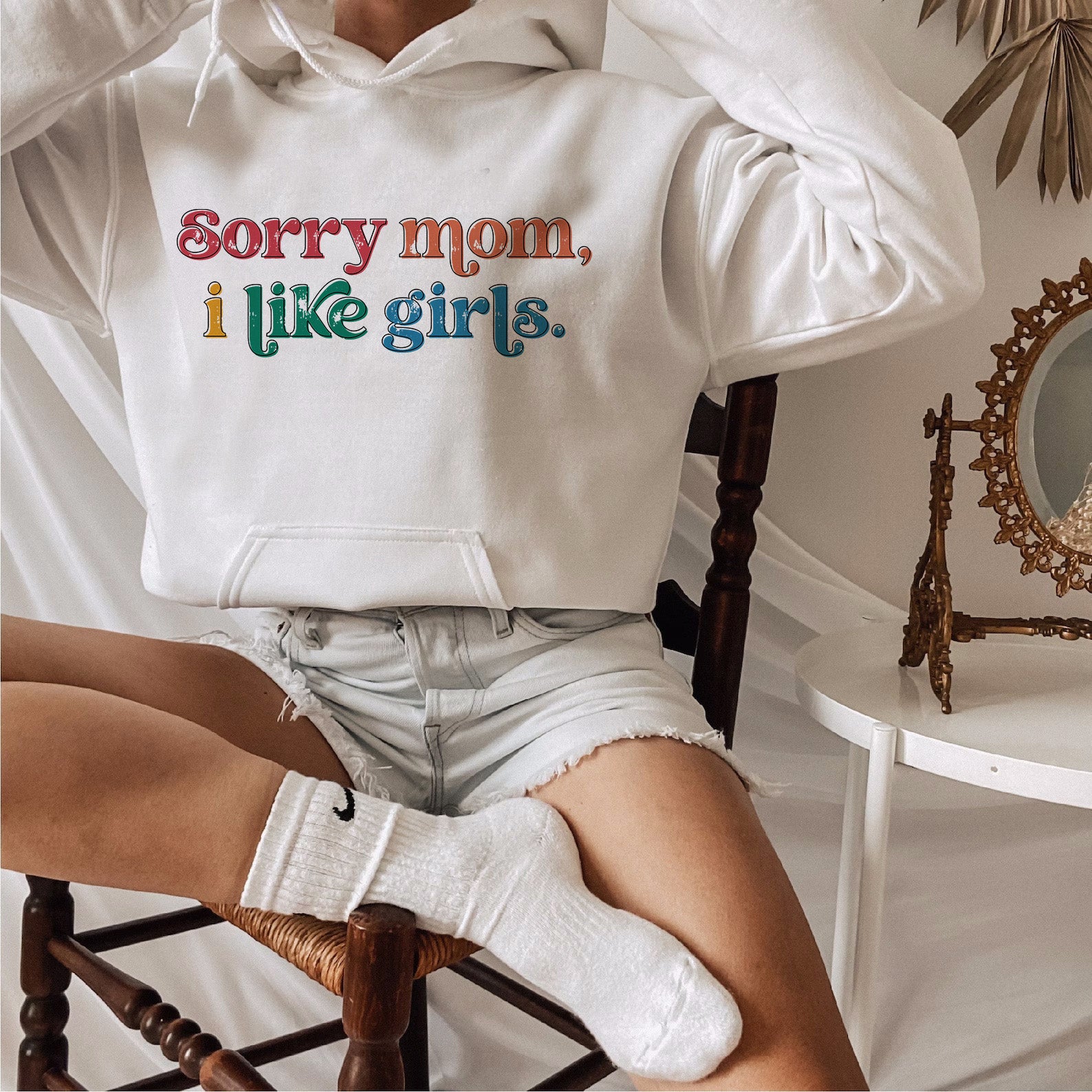 a woman sitting on a chair wearing a white hoodie