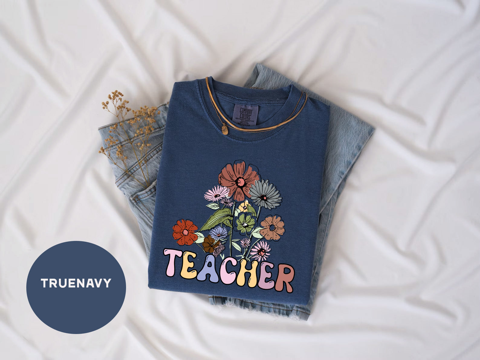 a t - shirt that says teacher on it next to a pair of jeans