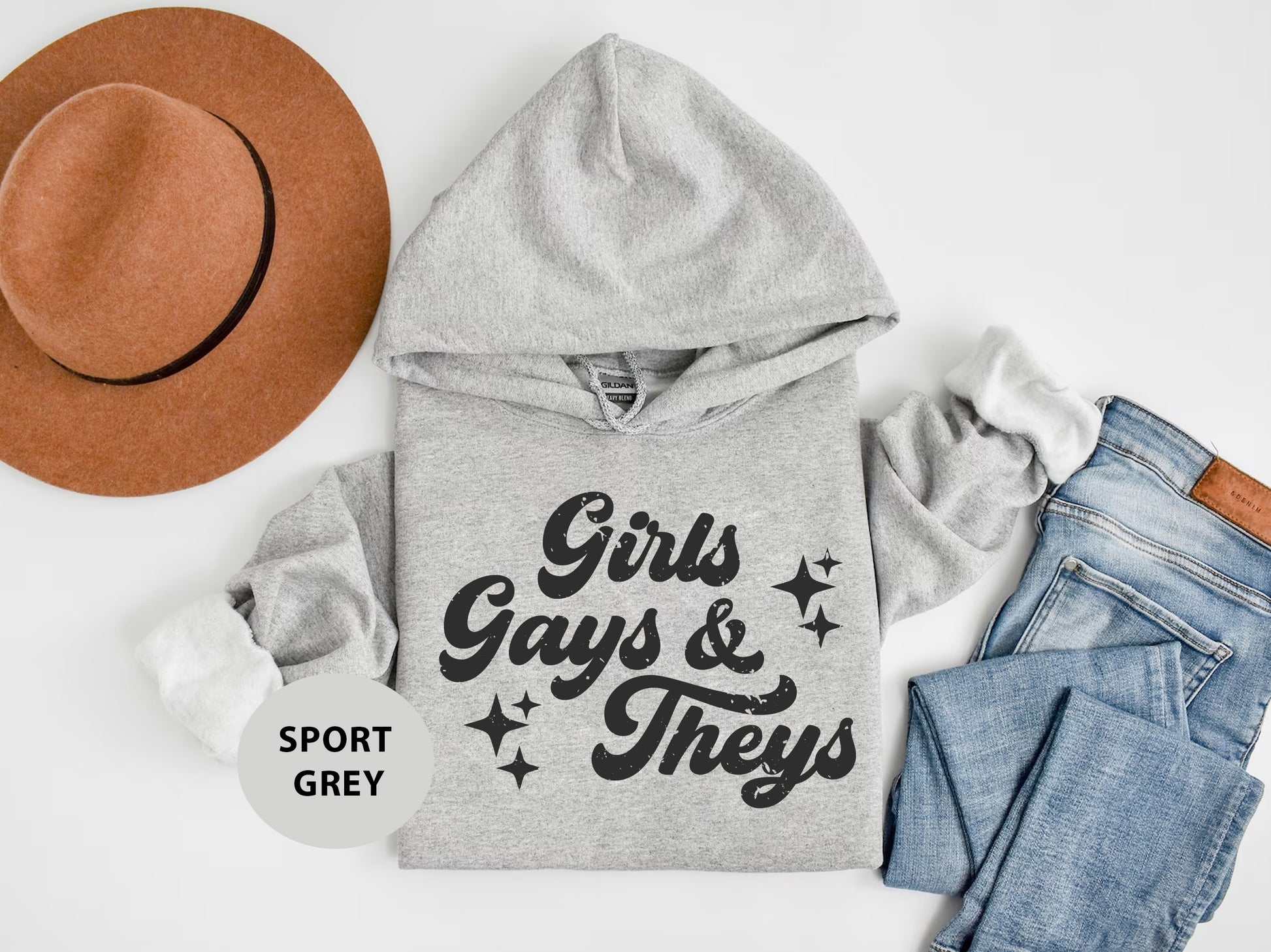 a hoodie, jeans, and hat are laid out on a white surface