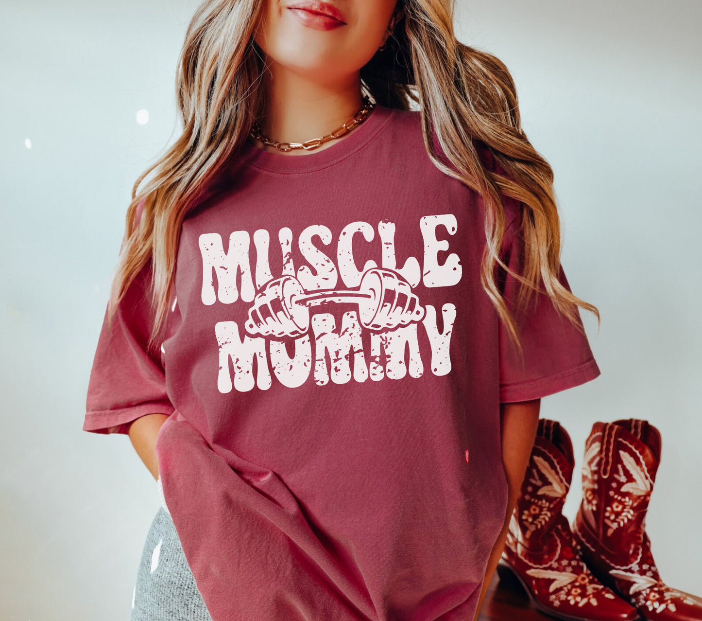 a woman wearing a red shirt that says muscle mommy