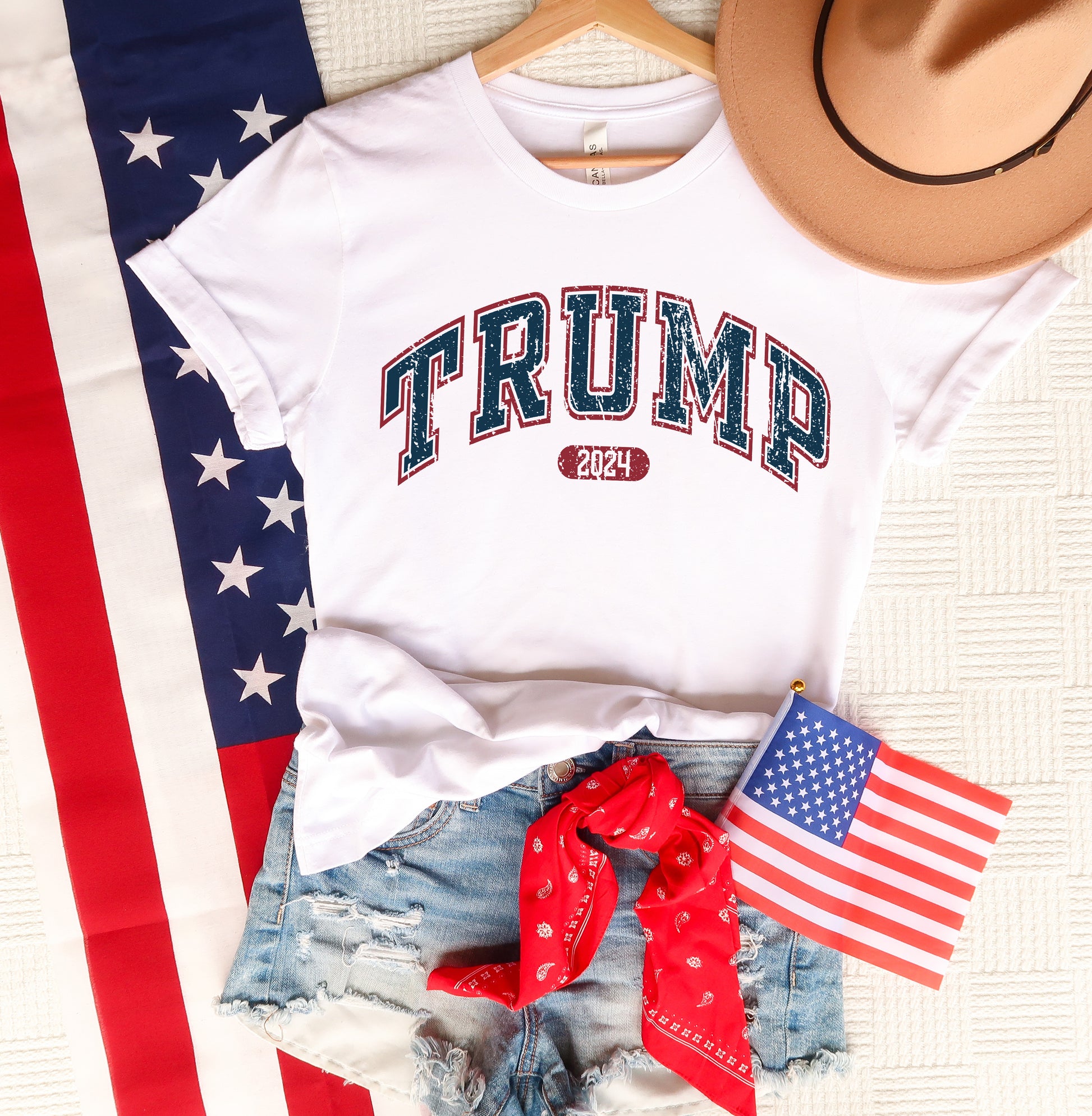 a white shirt that says trump next to a hat and american flag