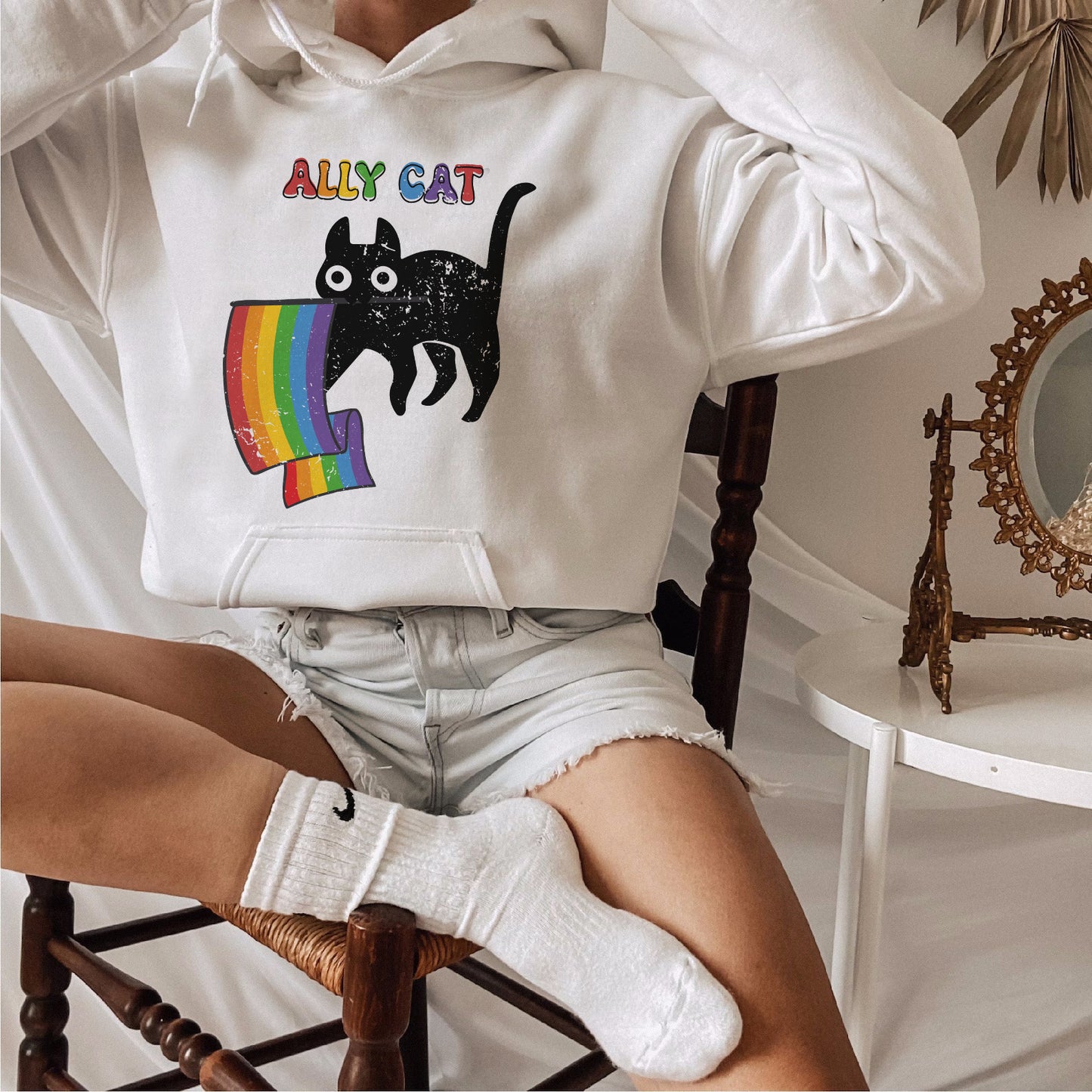 a woman sitting in a chair wearing a white hoodie with a cat on it