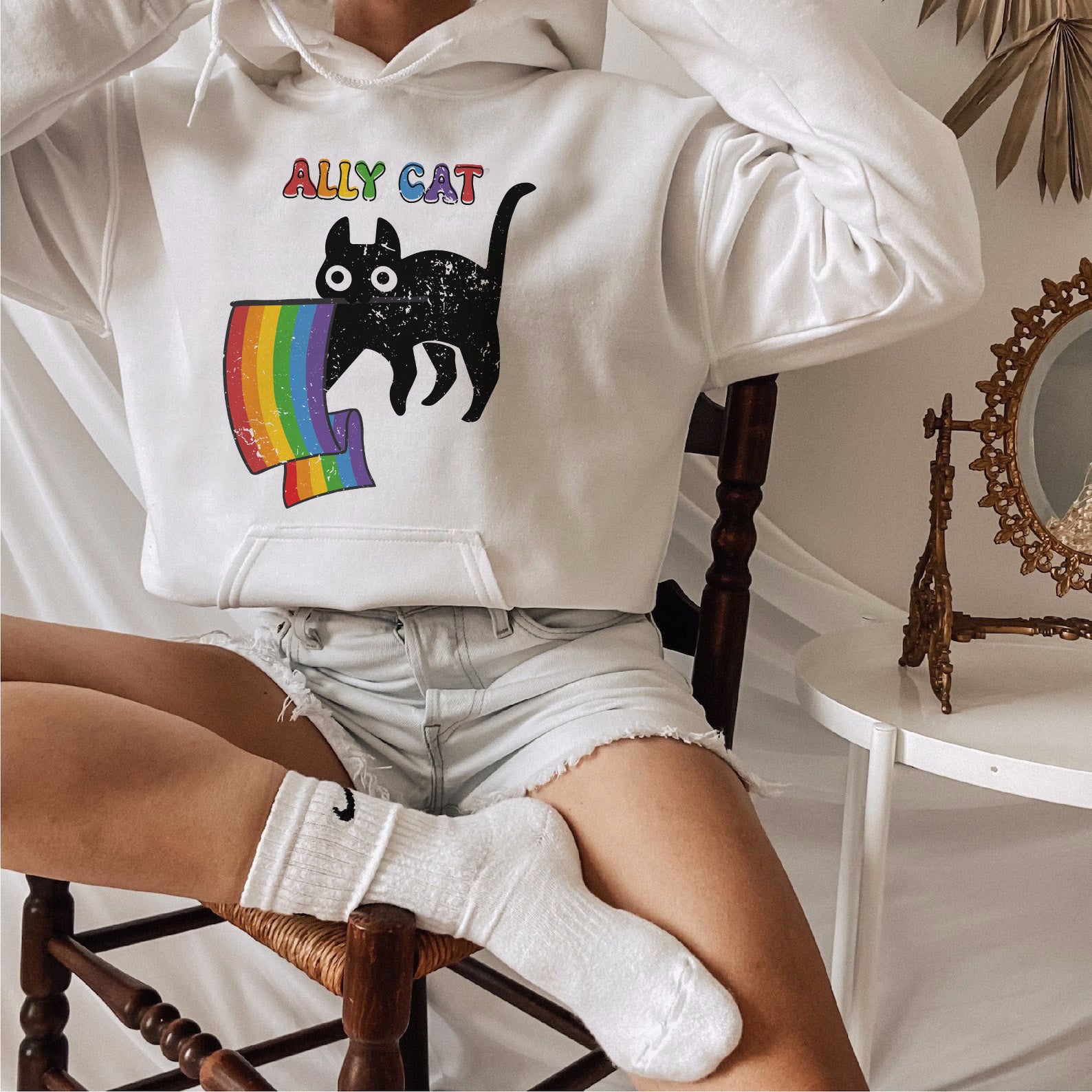 a woman sitting in a chair wearing a white hoodie with a cat on it