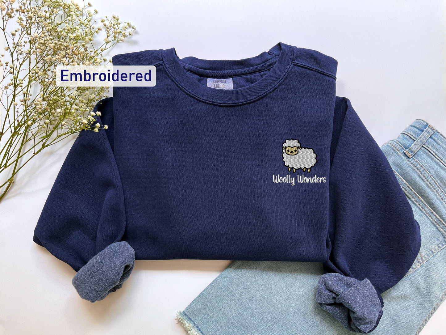a blue sweater with a sheep embroidered on it