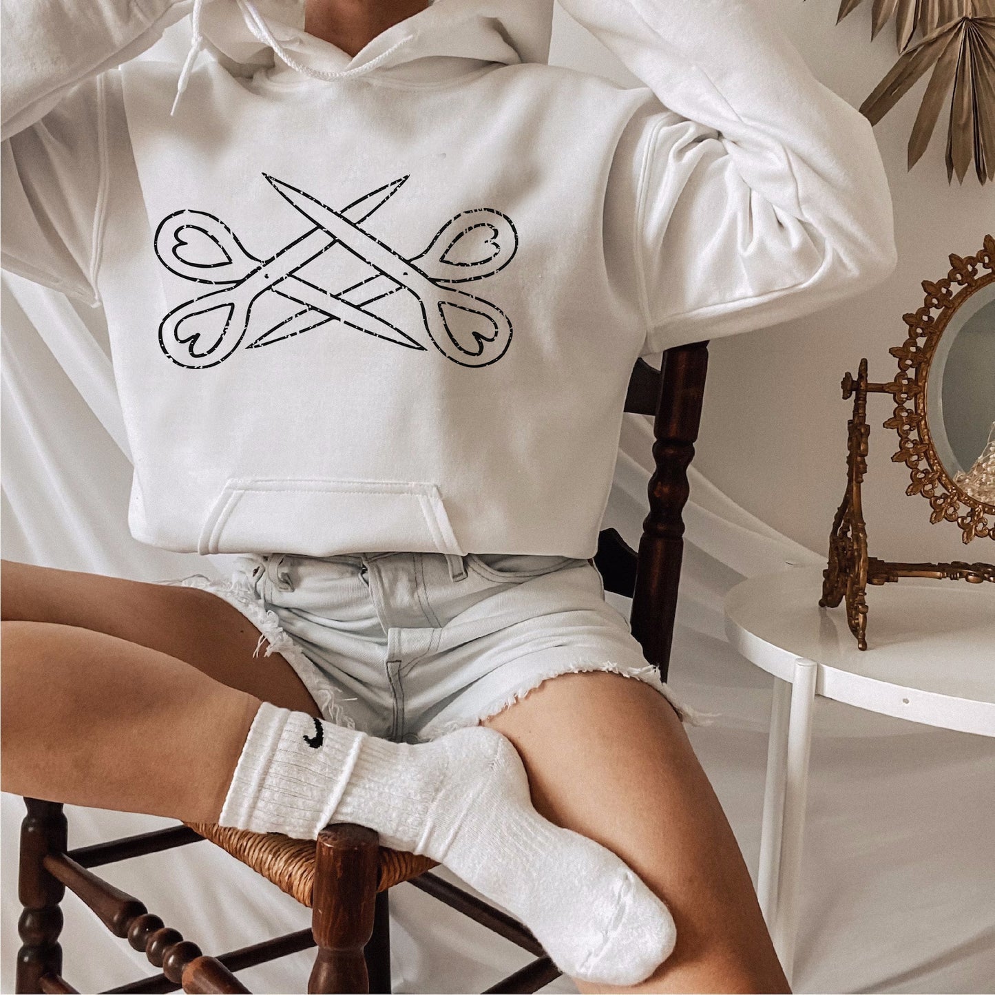 a woman sitting on a chair wearing a white hoodie
