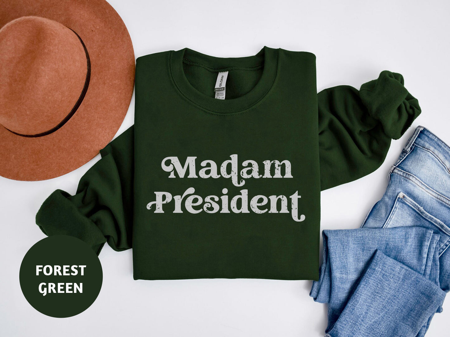 a green shirt that says madam president next to a hat