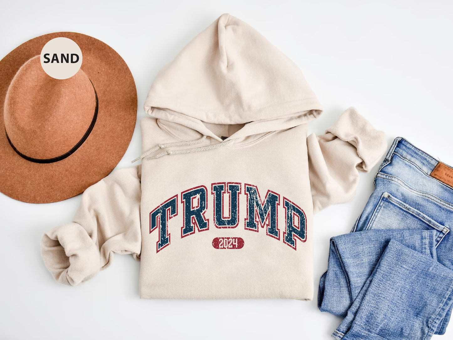 a hat, sweatshirt, jeans, and a pair of shoes on a white surface