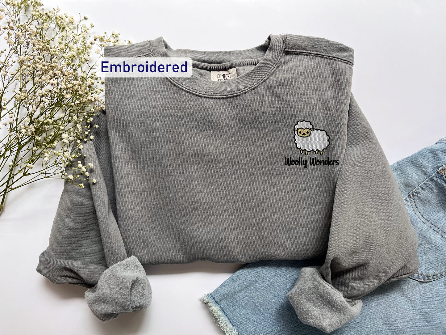 a gray sweatshirt with a sheep embroidered on it