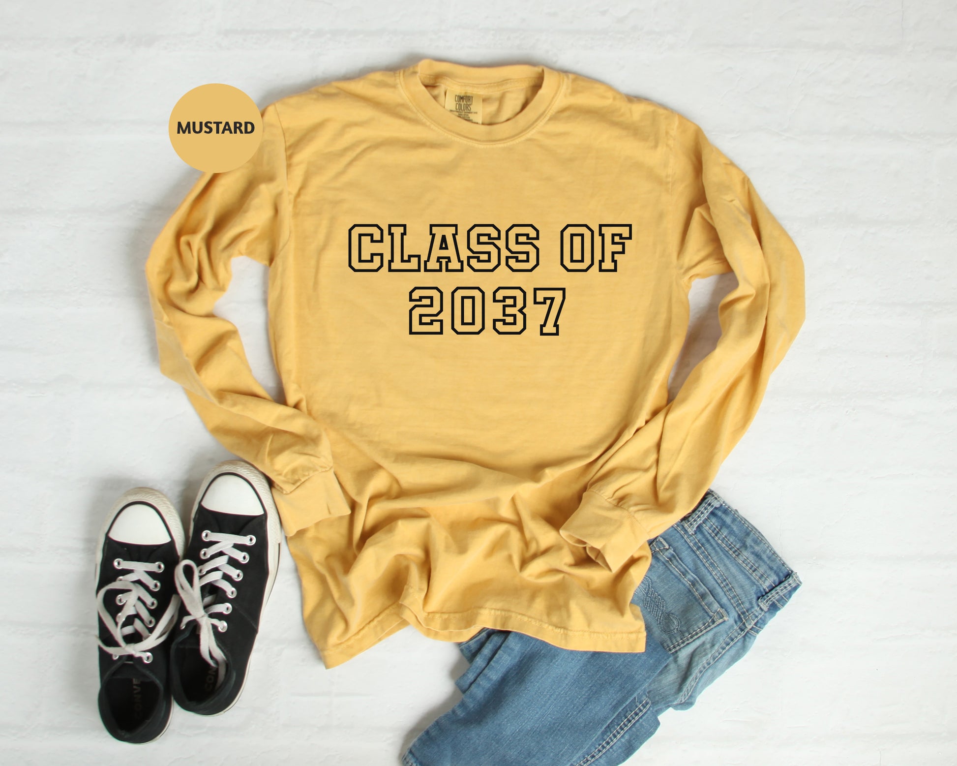 a yellow shirt that says class of 2007 next to a pair of black sneakers