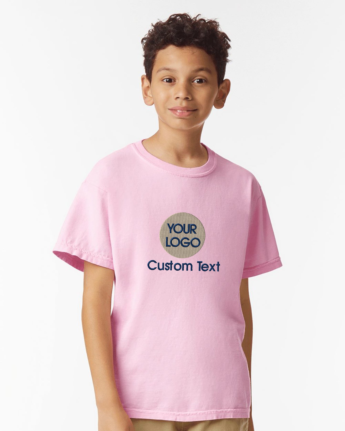 a young boy wearing a pink t - shirt and tan pants