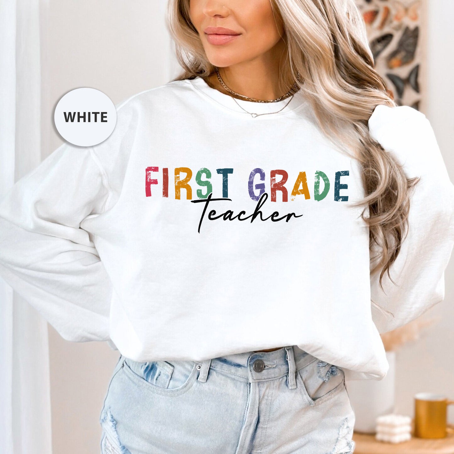 a woman wearing a white sweatshirt that says first grade teacher