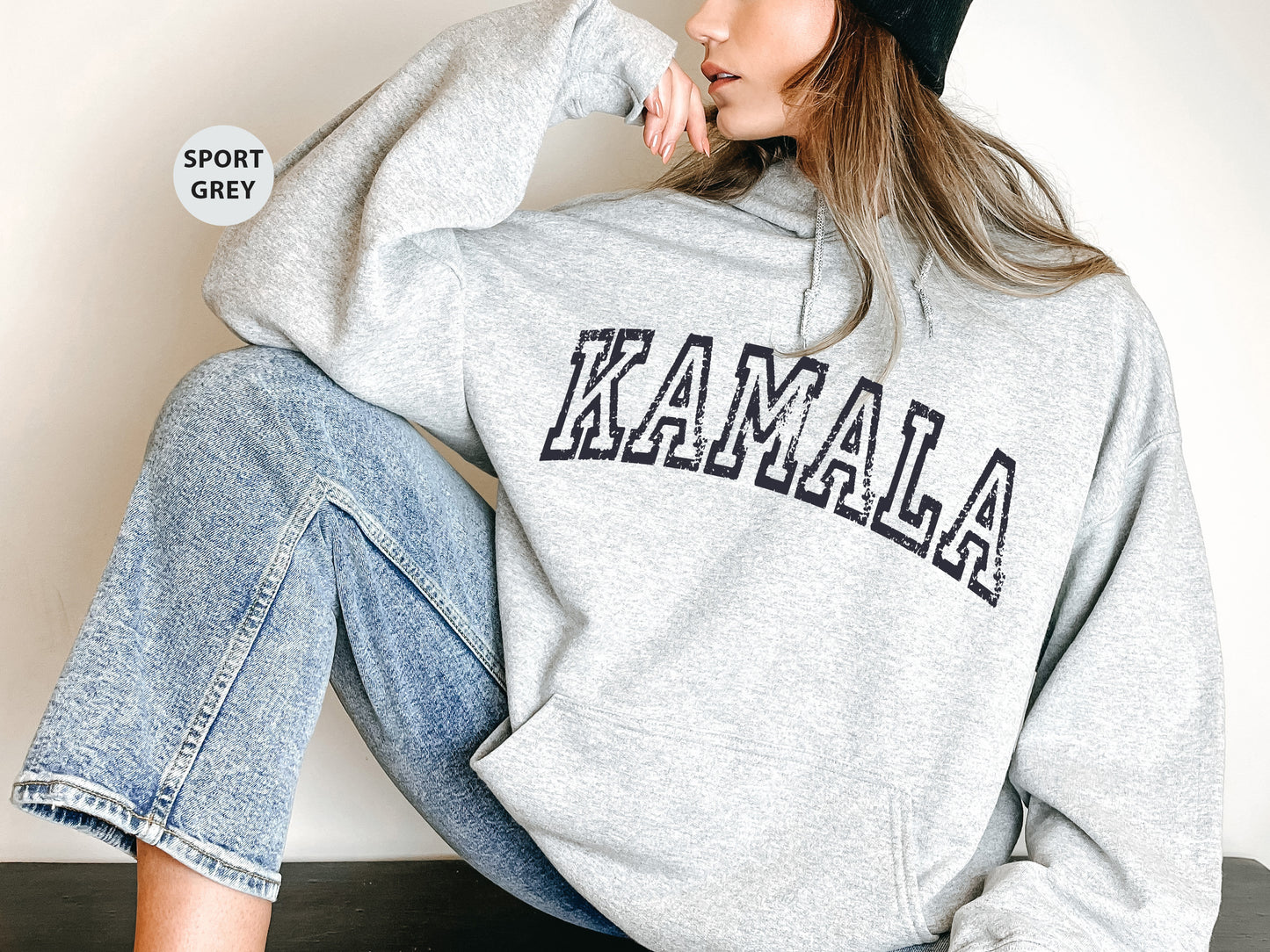 a woman sitting on the ground wearing a sweatshirt and beanie